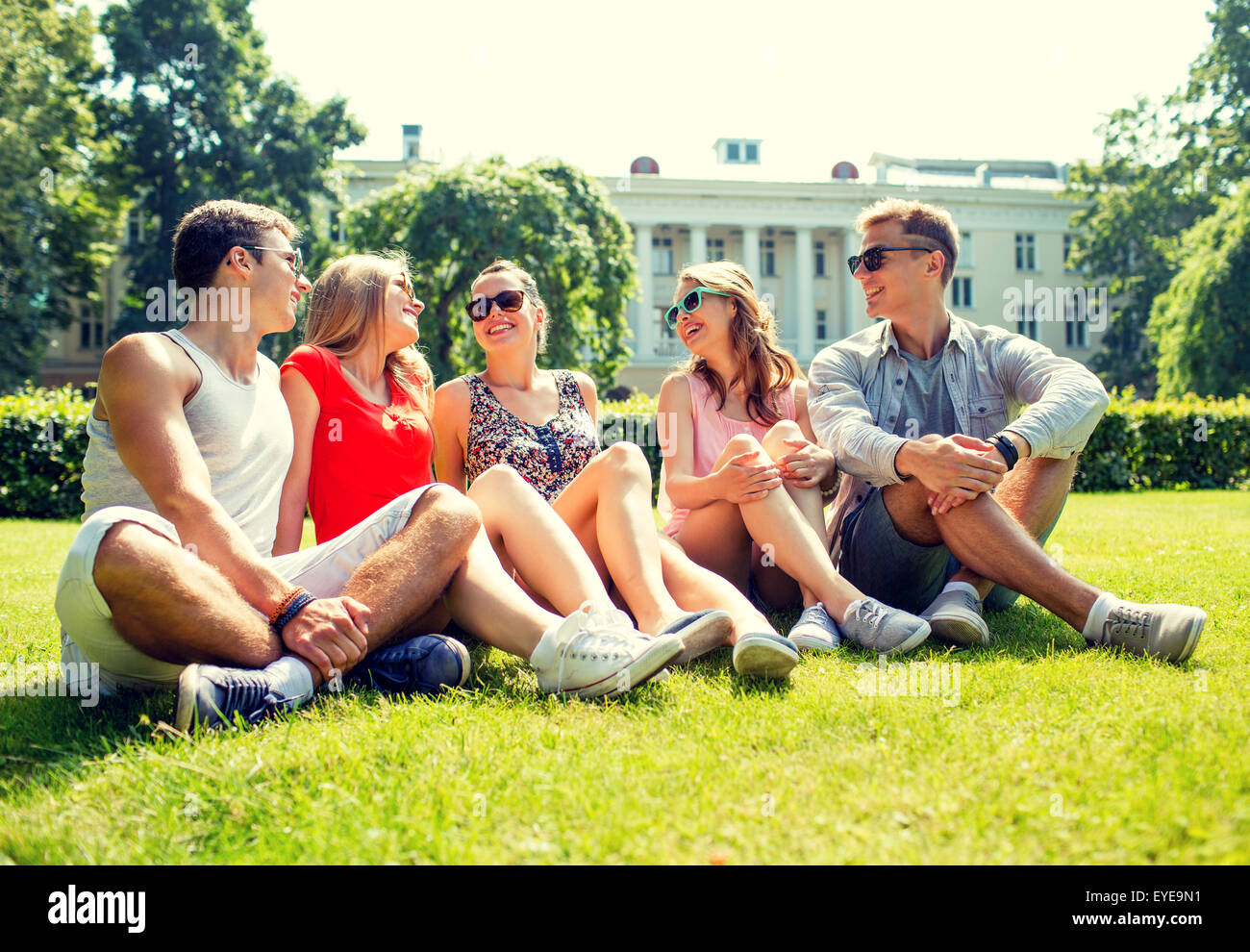 group of smiling friends outdoors sitting in park Stock Photo - Alamy
