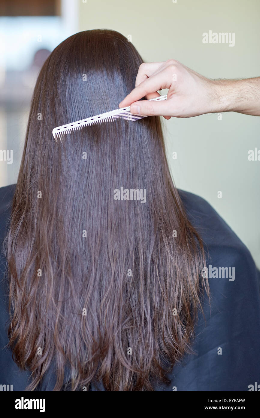 hand with comb combing woman hair at salon Stock Photo
