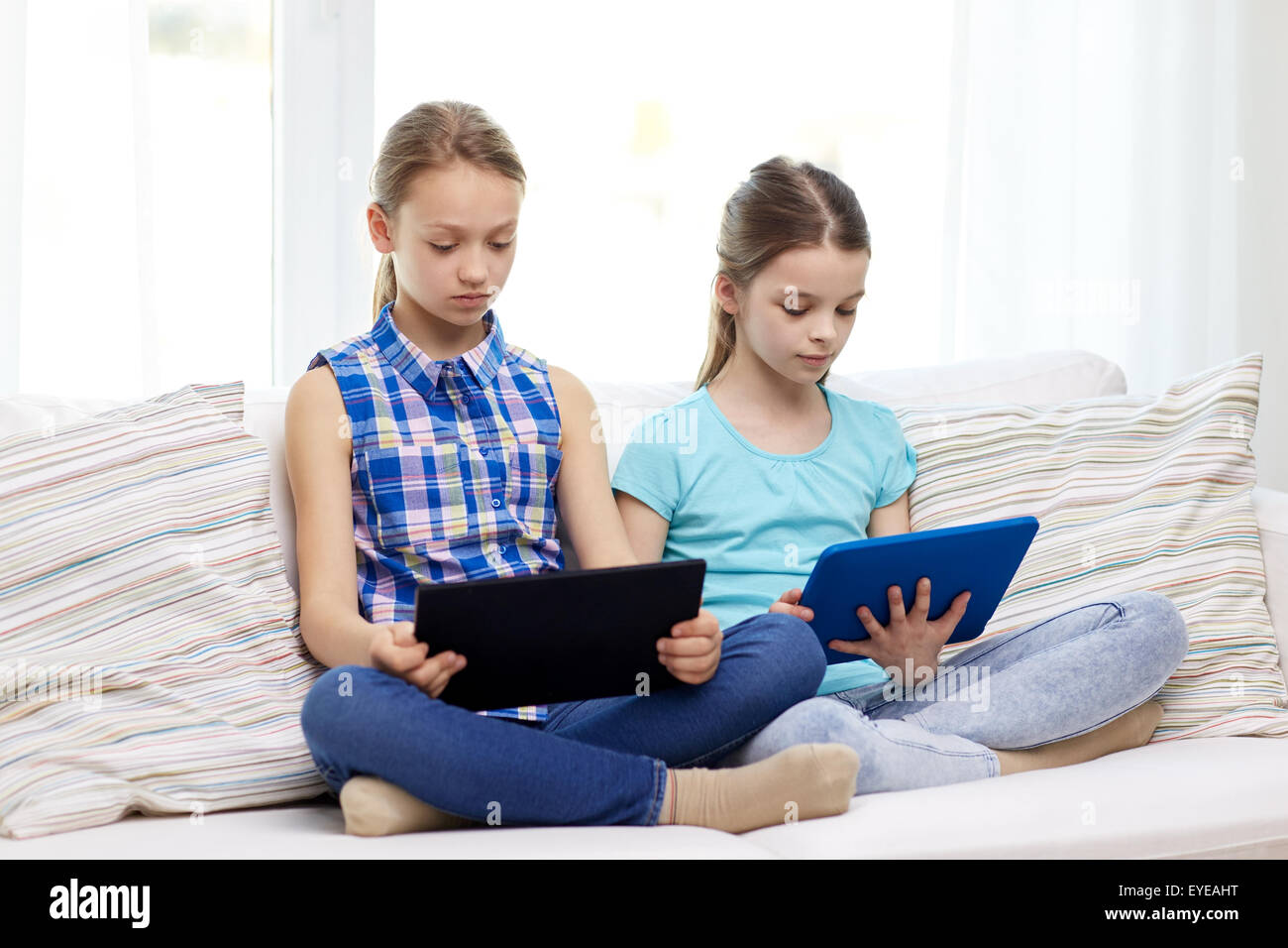 girls with tablet pc sitting on sofa at home Stock Photo - Alamy