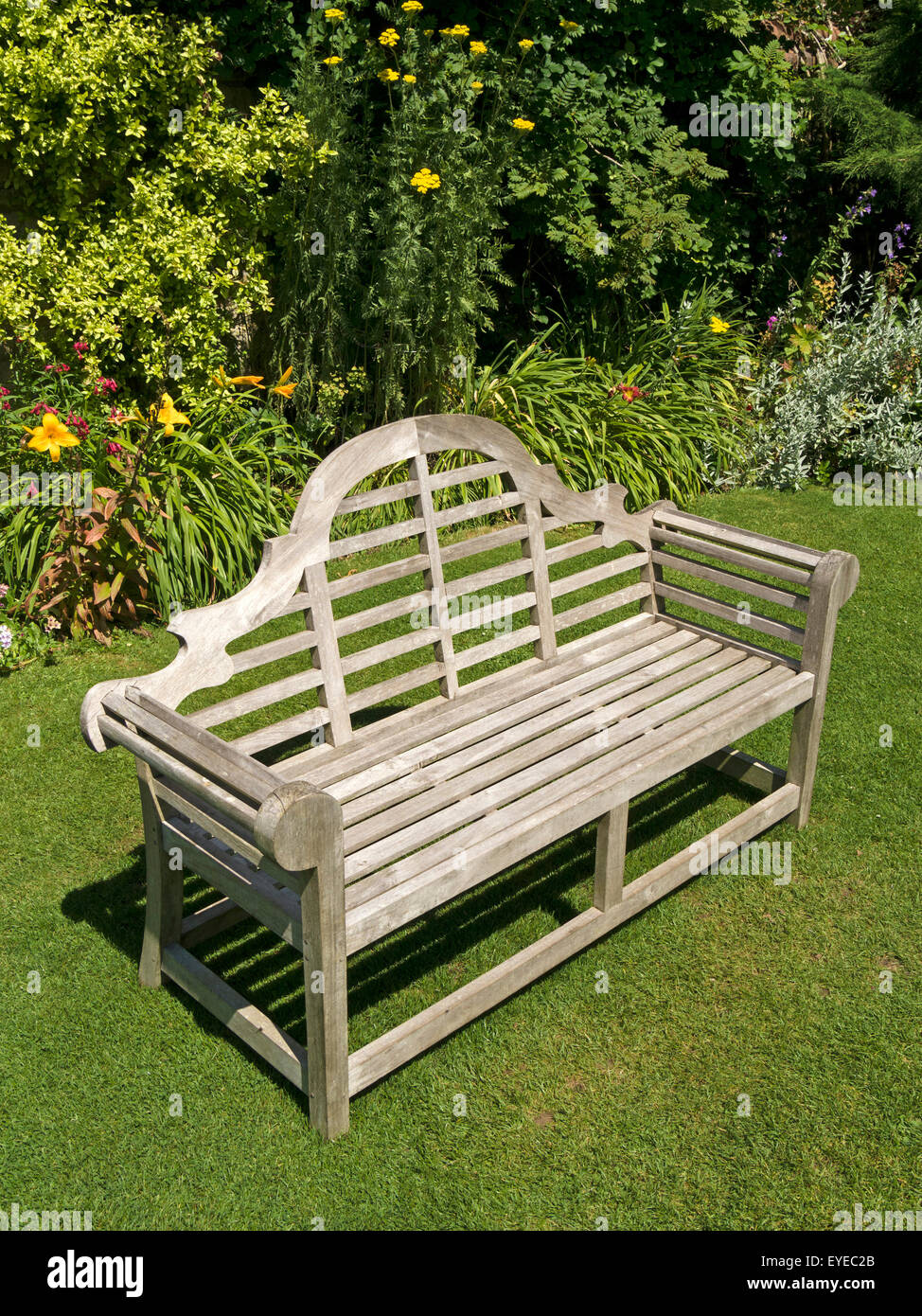 Ornate wooden garden bench seat on green lawn, Barnsdale 