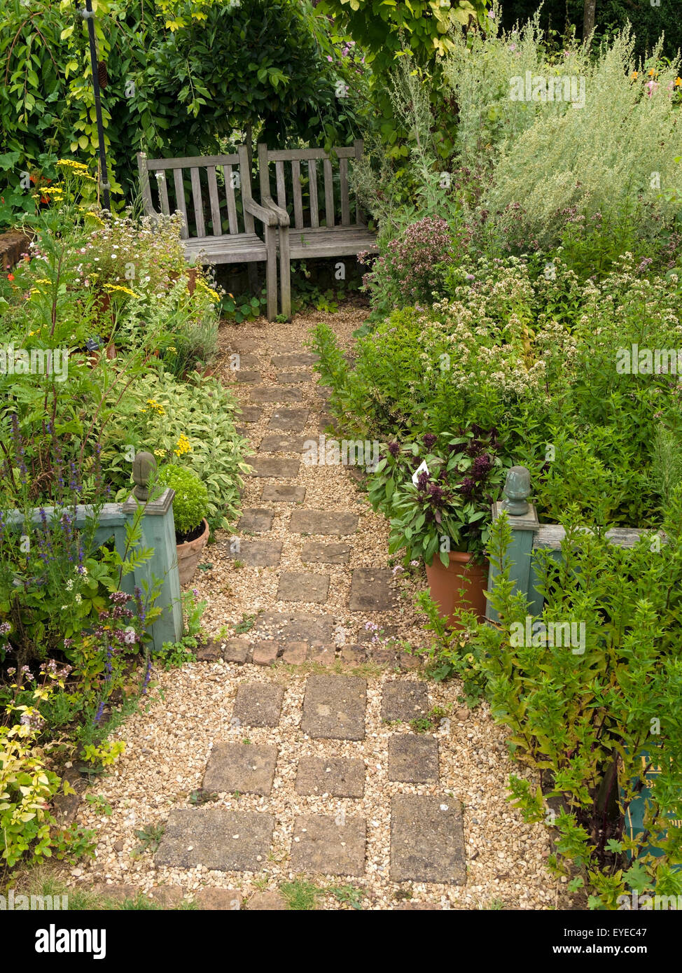 Small English cottage garden with paved and gravel path, borders and wooden garden seats, Barnsdale Gardens, Rutland, England,UK Stock Photo