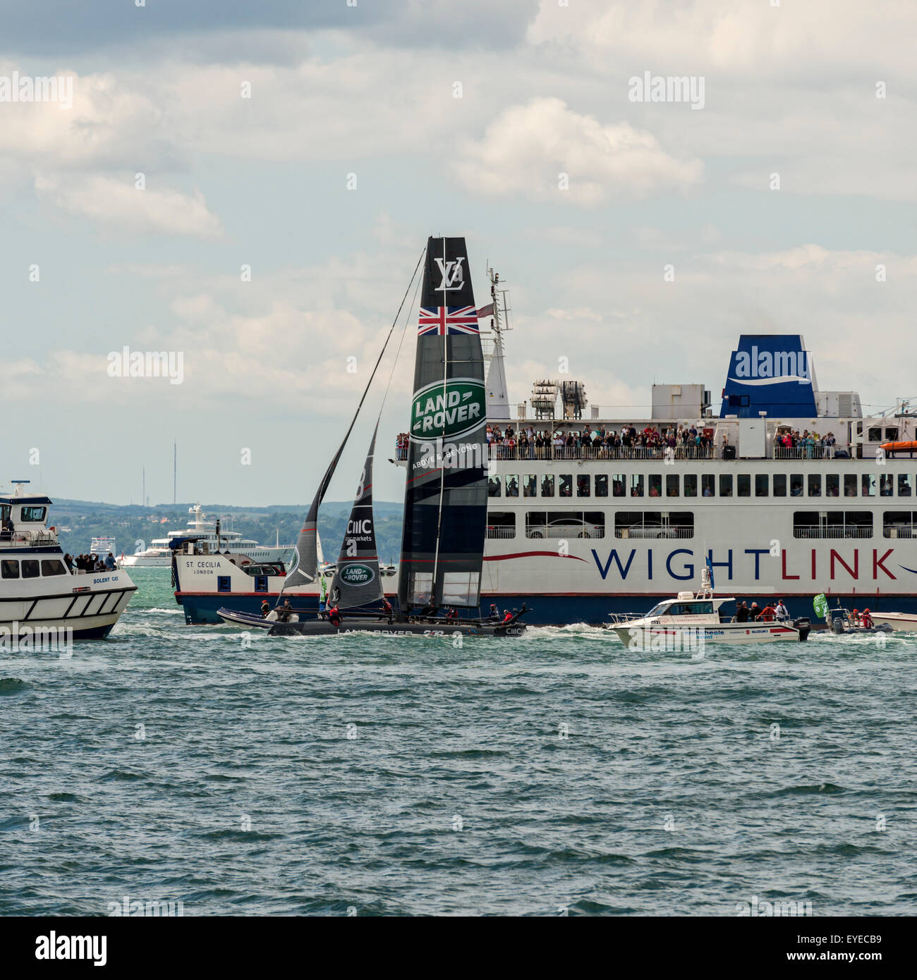 The Team Land Rover BAR America's Cup boat passes a Wight Link car ferry during the America's Cup World Series in Portsmouth Stock Photo
