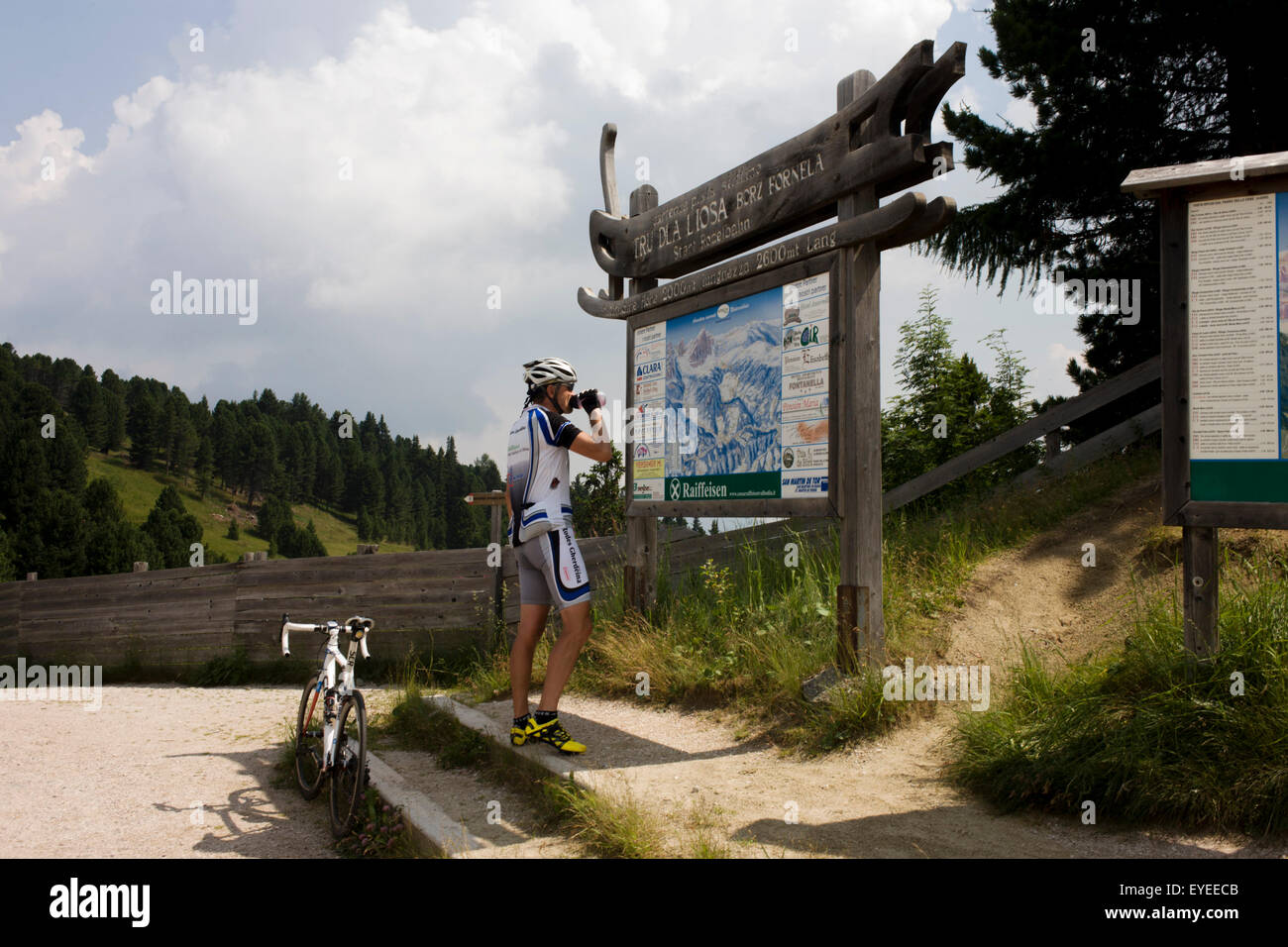 Resting cyclist consults map of Dolomites mountain range while on the summit of the Wurzjoch Pass Stock Photo