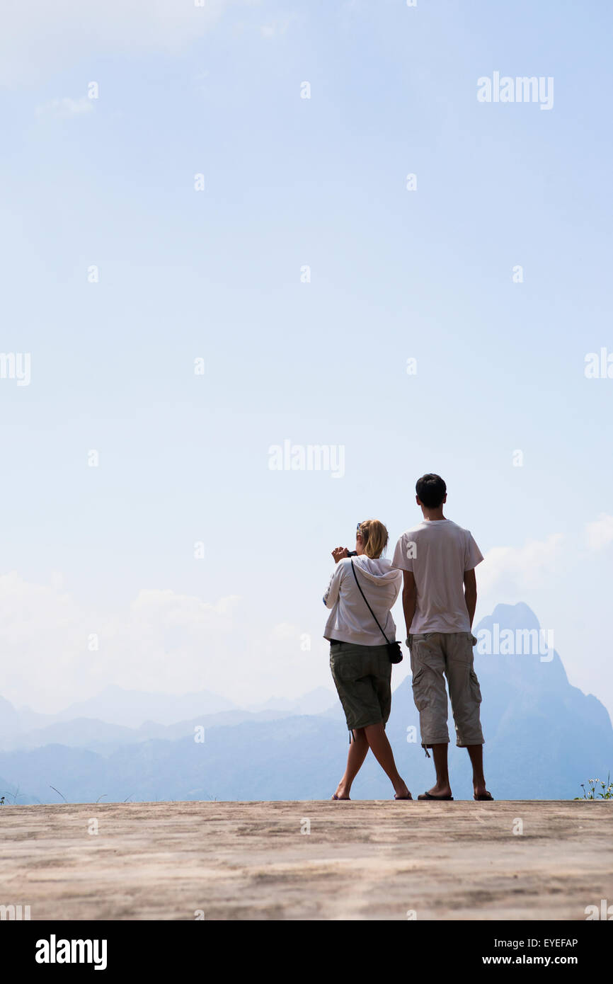 A couple stands at a lookout with a view over the valley between Luang Prabang and Vang Vieng; Laos Stock Photo