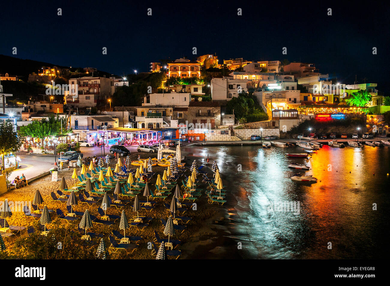 Colourful lights illuminate and reflect on the water in the harbour; Bali, Crete, Greece Stock Photo