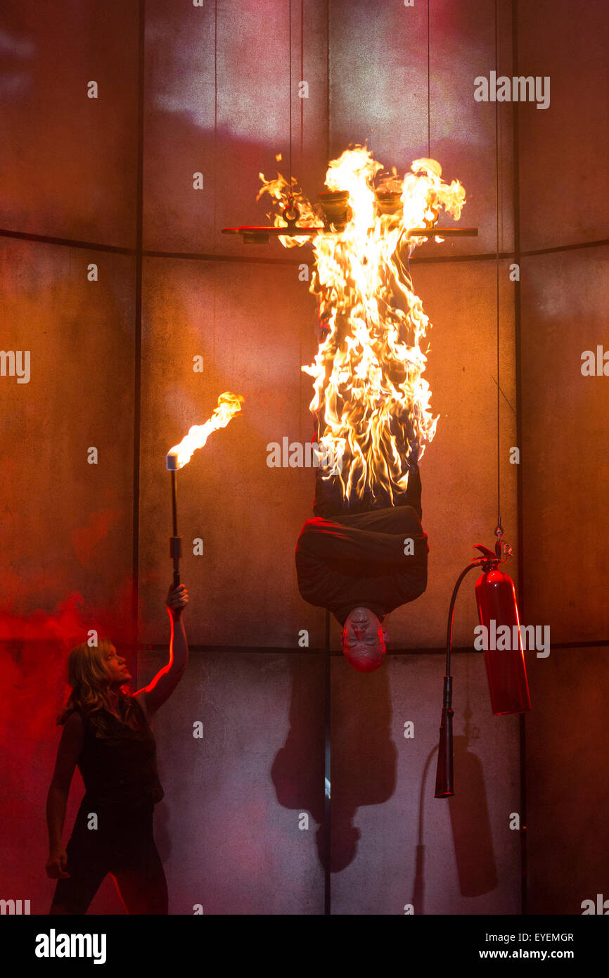 London, UK. 28 July 2015. Pictured: Magician Jonathan Goodwin is set on fire by his wife/assistant Katie. Impossible, the biggest magic show in decades, premieres are the Noel Coward Theatre in London. Magicians and illusionists such as Jamie Allan, Damien O'Brien, Ali Cook, Chris Cox, Jonathan Goodwin, Ben hart, Luis de Matos and Katherine Mills will perform in the show directed by Anthony Owen from 25 July to 29 August 2015. Stock Photo