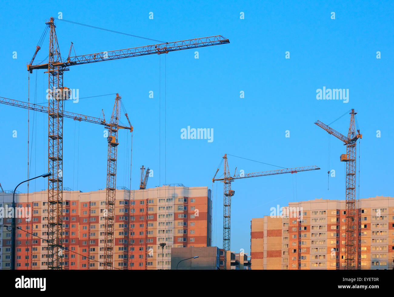 Cranes on construction site of new apartment buildings at sunset. Stock Photo