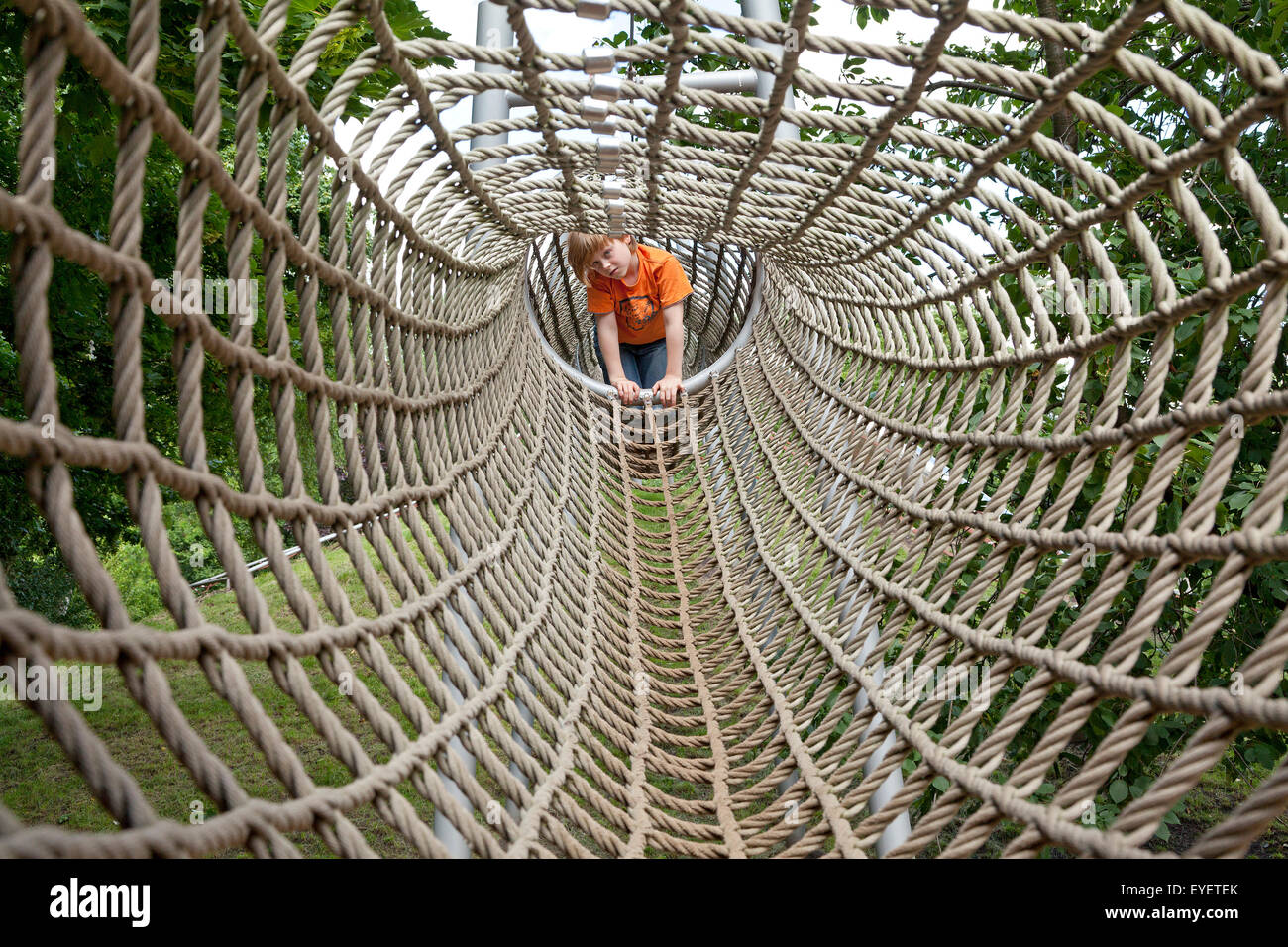young boy climbing through a rope tunnel on a playground Stock Photo Alamy