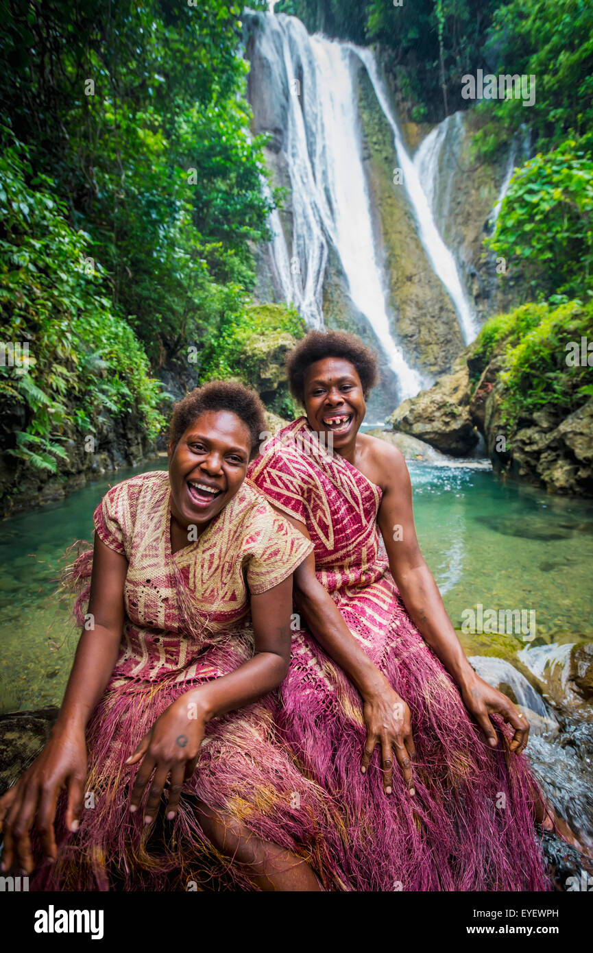 A waterfall on Tanna Island with two women in traditional costume in
