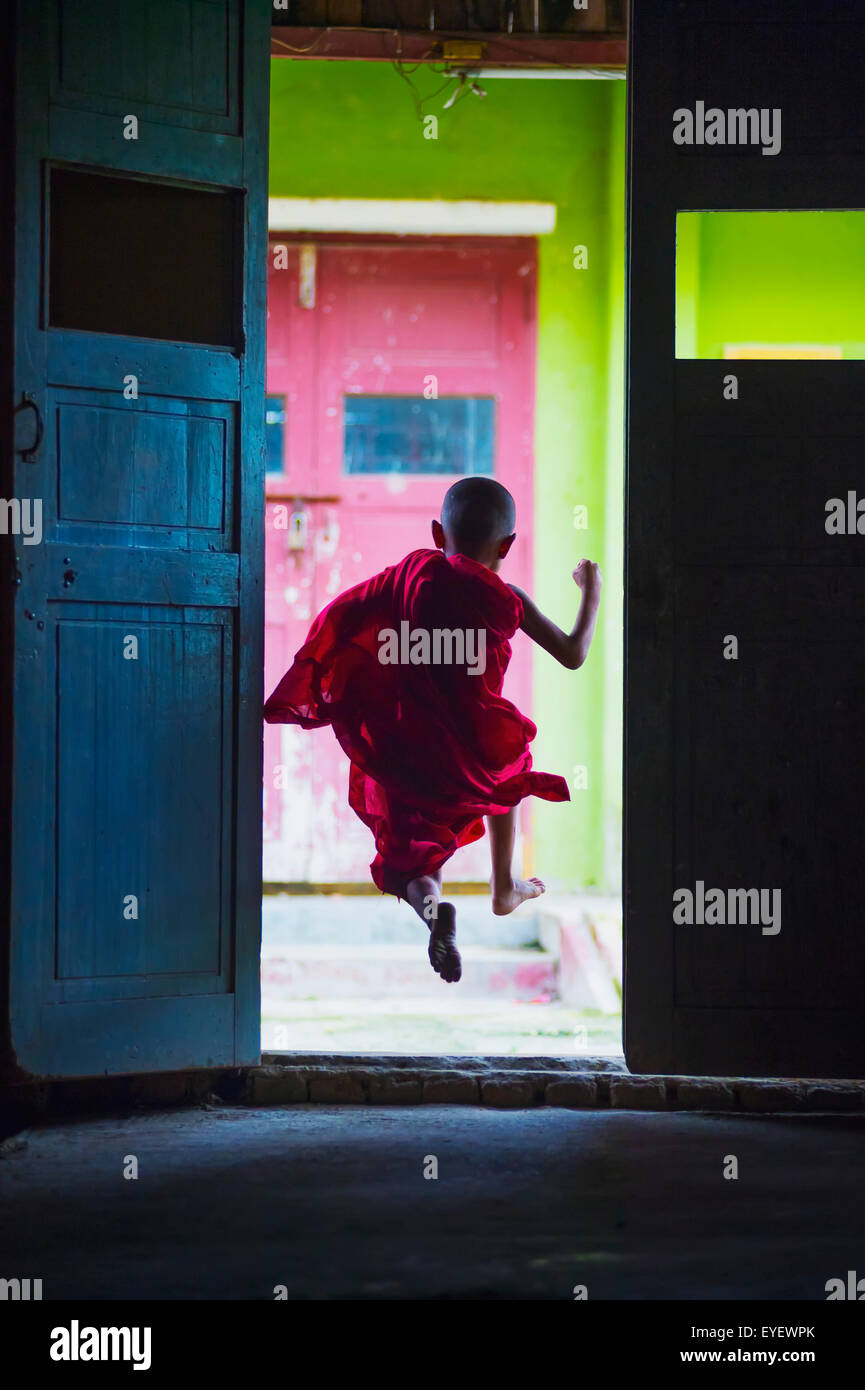 Young monk dances out of class; Yangoon, Myanmar Stock Photo