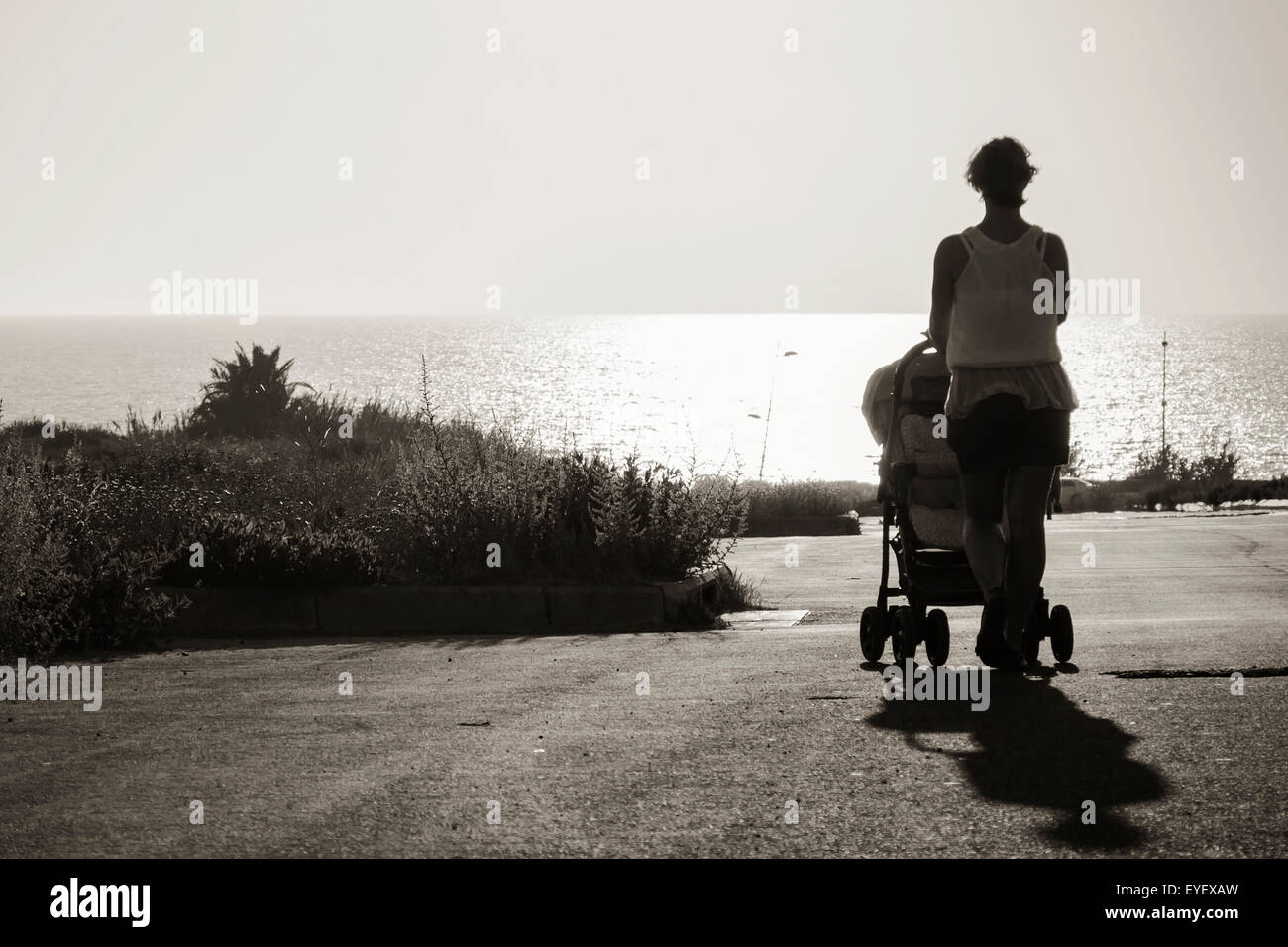 stretching into the distance to sea mother with stroller Stock Photo