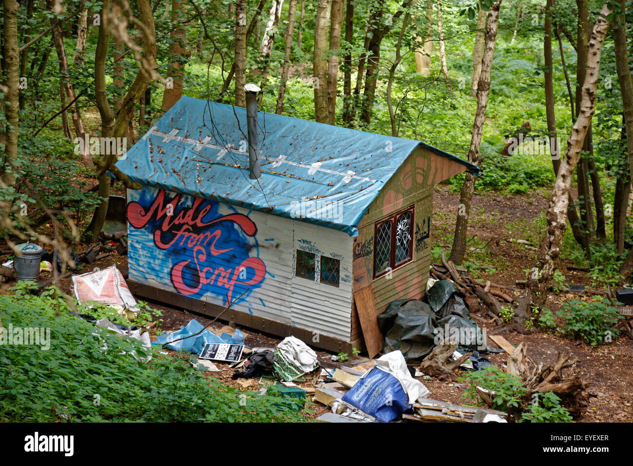 An 'Eco Village' home in woodland with 'Made from Scrap' painted on a wall  & surrounded by rubbish Stock Photo - Alamy