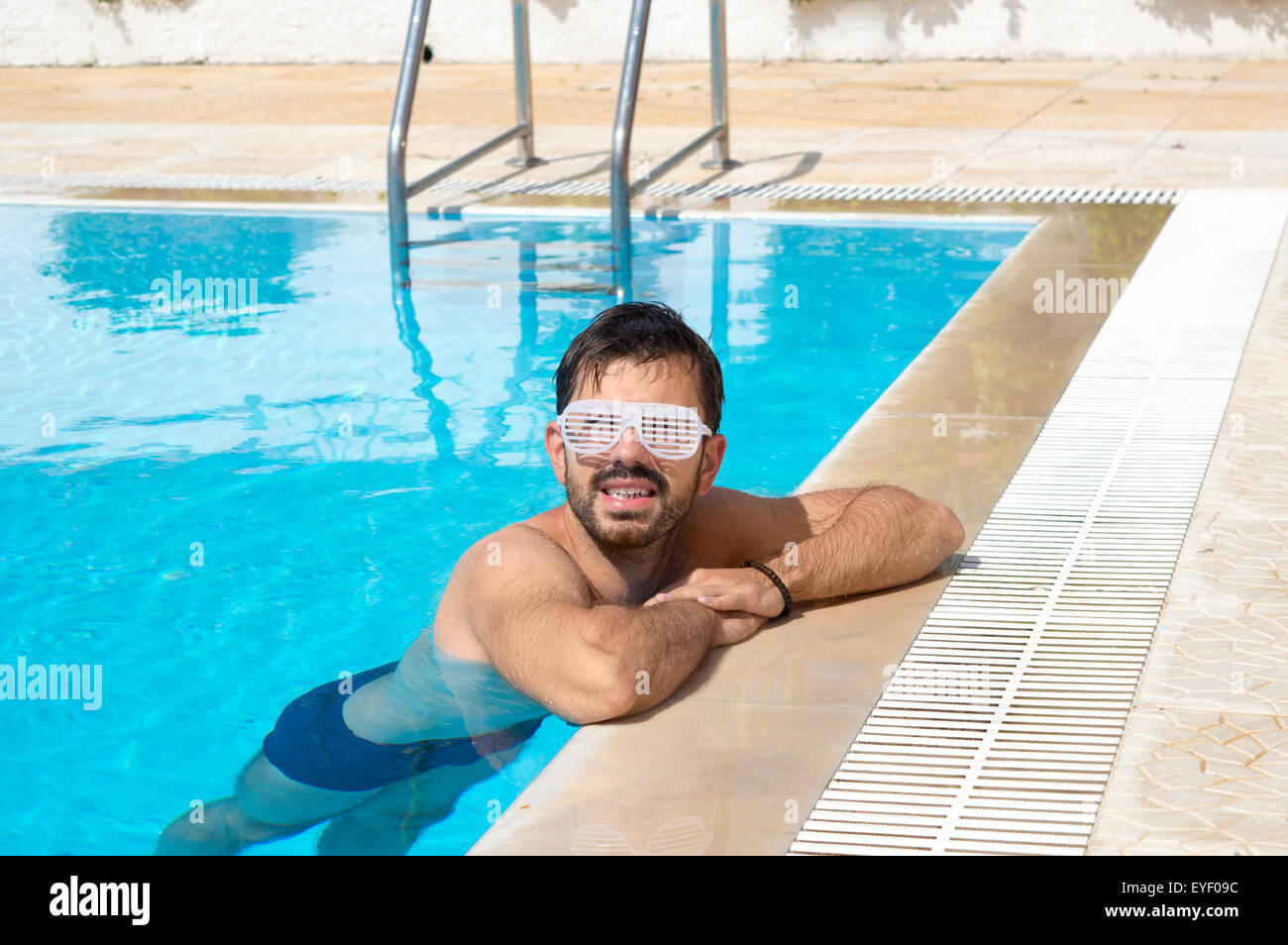 Man chilling in the pool wearing white dance party glasses Stock Photo