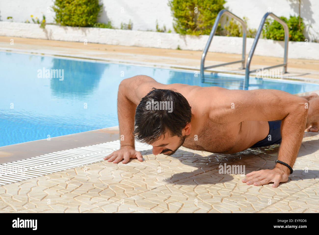 Bearded tanned man exercising by the pool Stock Photo