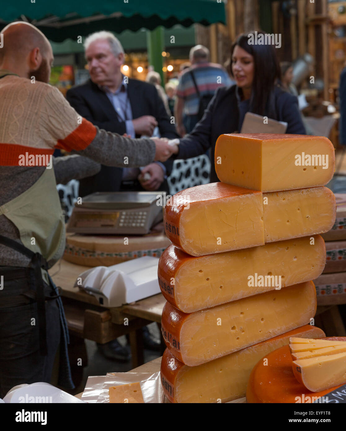 Cheese vendor and customers at a stall in the Borough Market, London