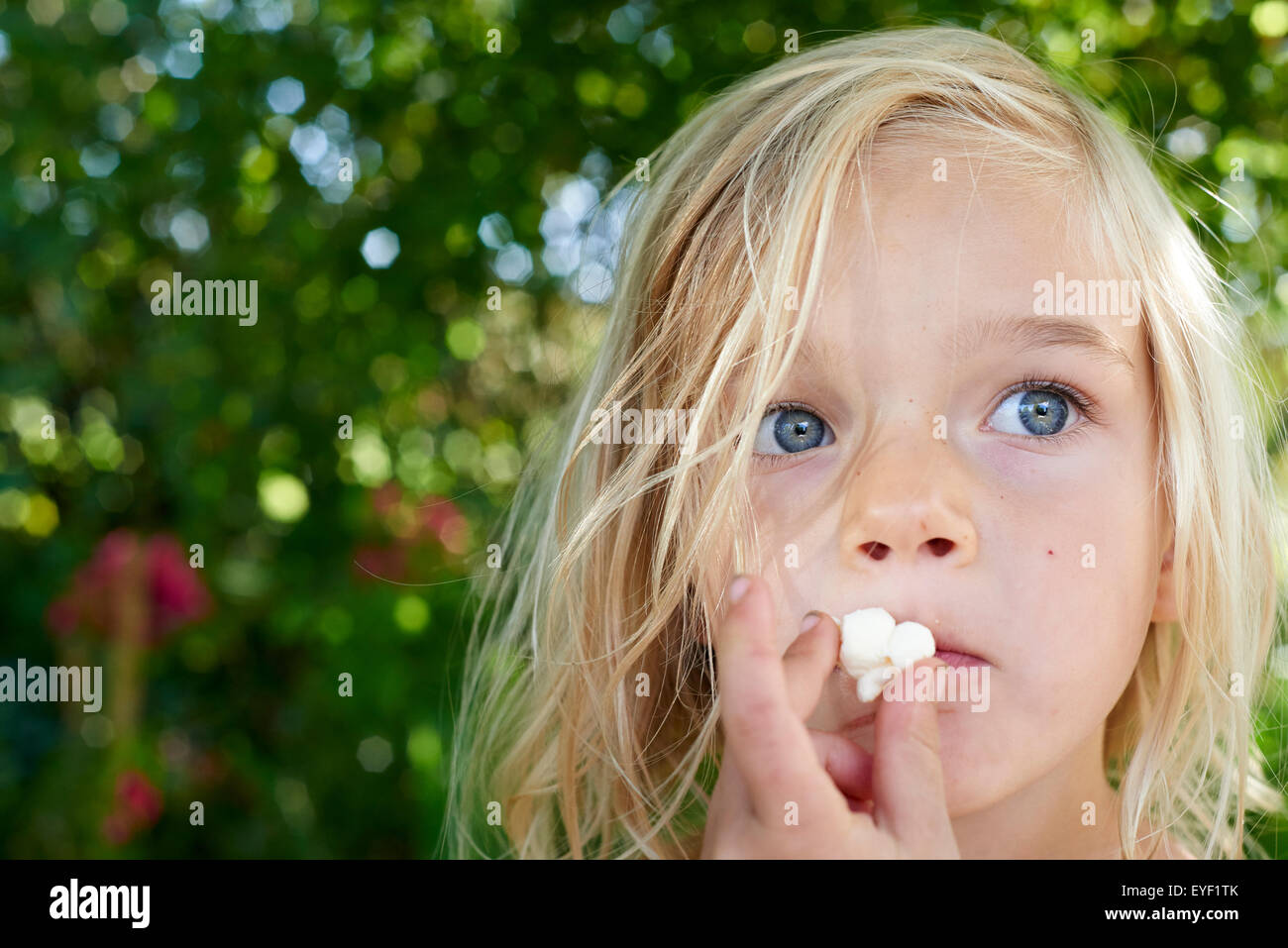 Child blond girl eating popcorn outside Stock Photo