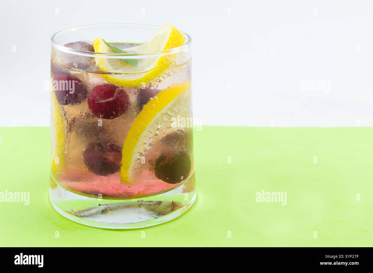 Natural raspberry fruit cocktail with ice, lemon and sliced fruits in a crooked glass. Cold drink Stock Photo