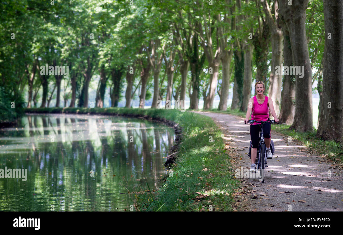 Woman cycling along French Canal Stock Photo