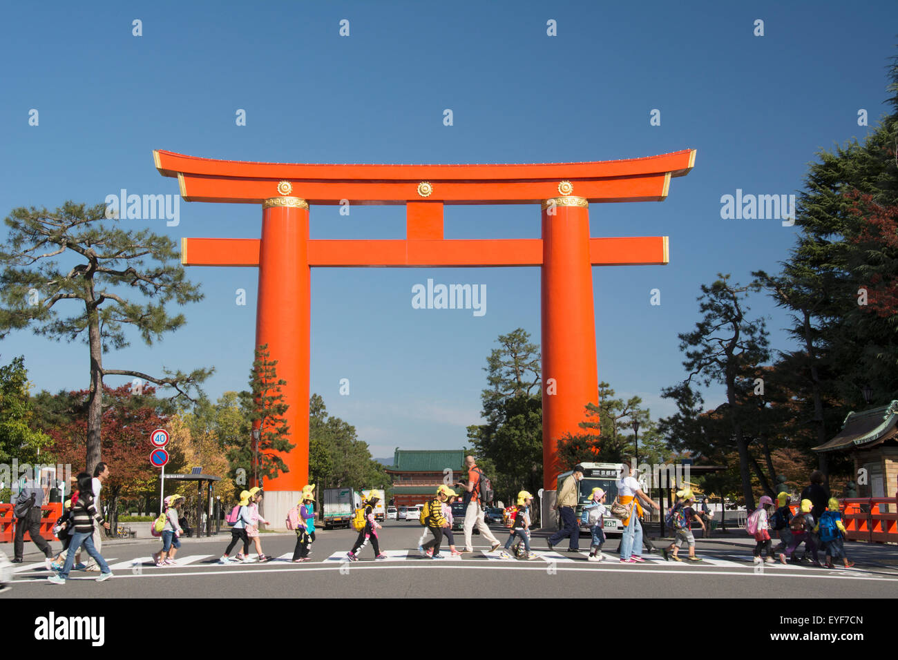 Large tori gate and pedestrians walking across the street; Kyoto, Japan Stock Photo