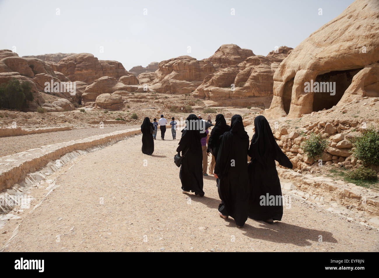 Local women walking into the site; Petra, Jordan Stock Photo