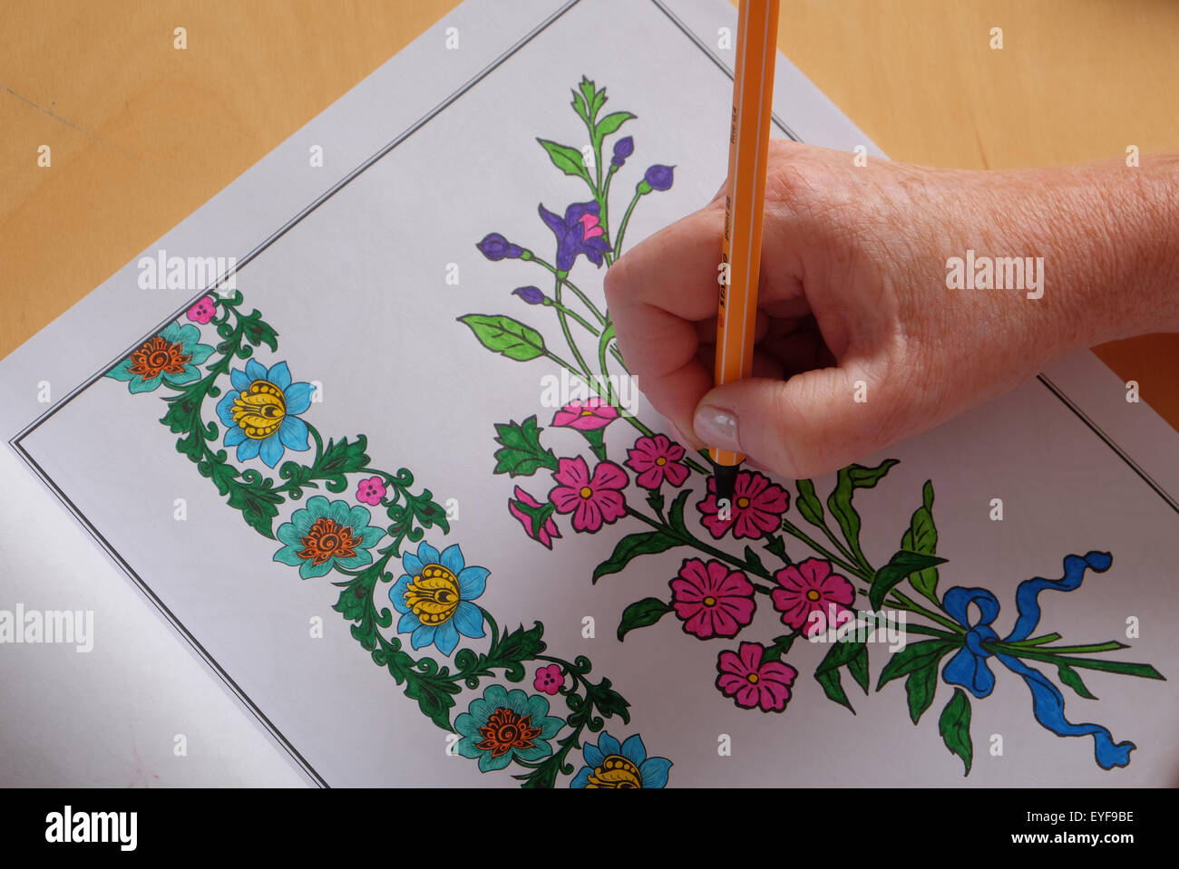 An adult woman colouring in a vintage design colouring in book, a new trend in relaxation for adults Stock Photo