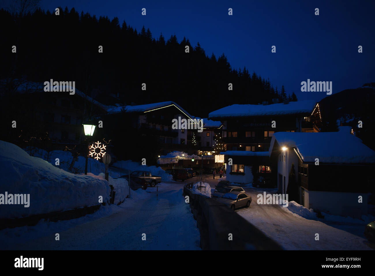 Snow covered rooves in the Alpine village at night with snowflake light and Christmas decorations; Filzmoos, Austria Stock Photo