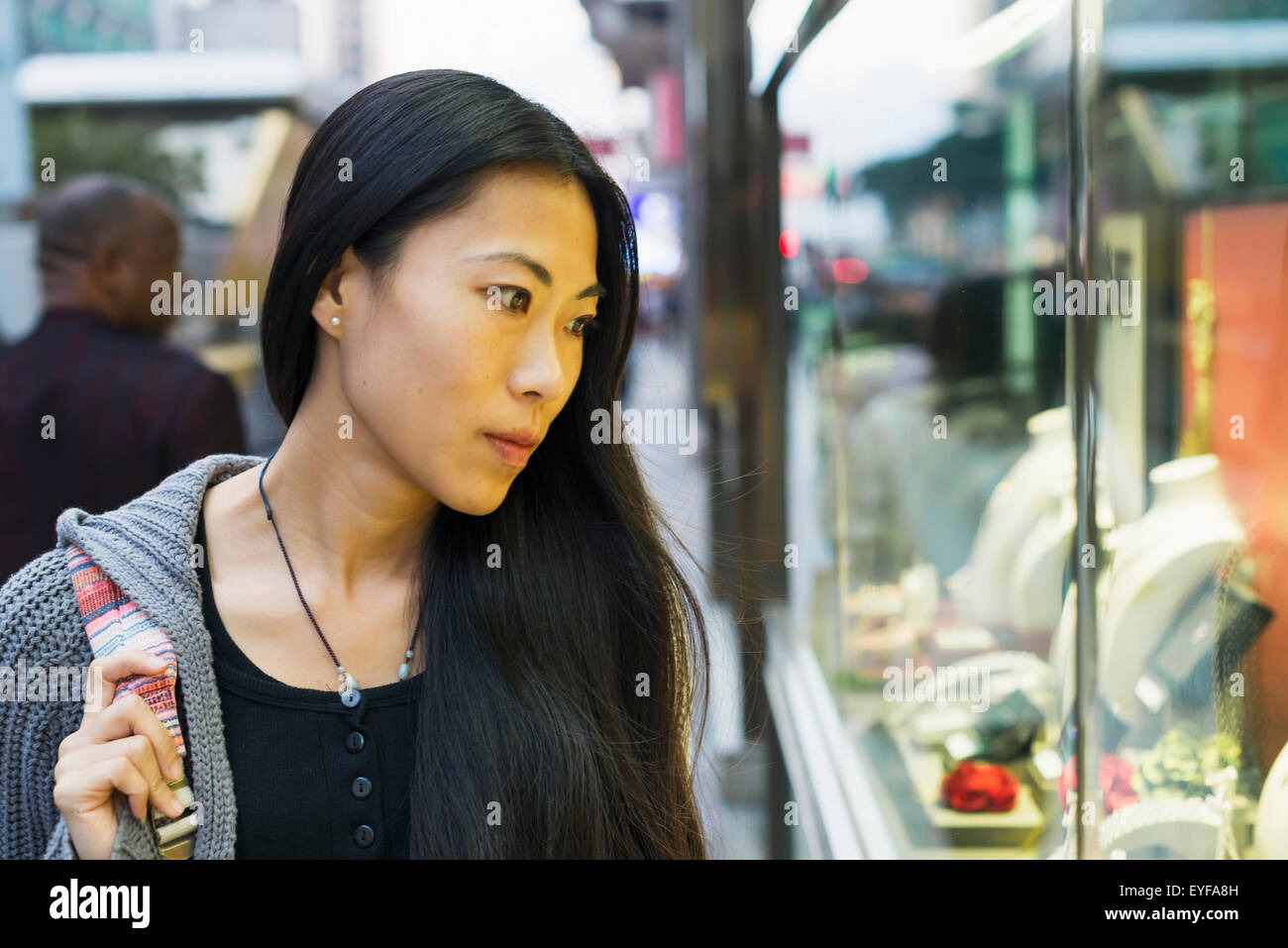 A young woman window shopping at the retail shops along the street, Kowloon; Hong Kong, China Stock Photo