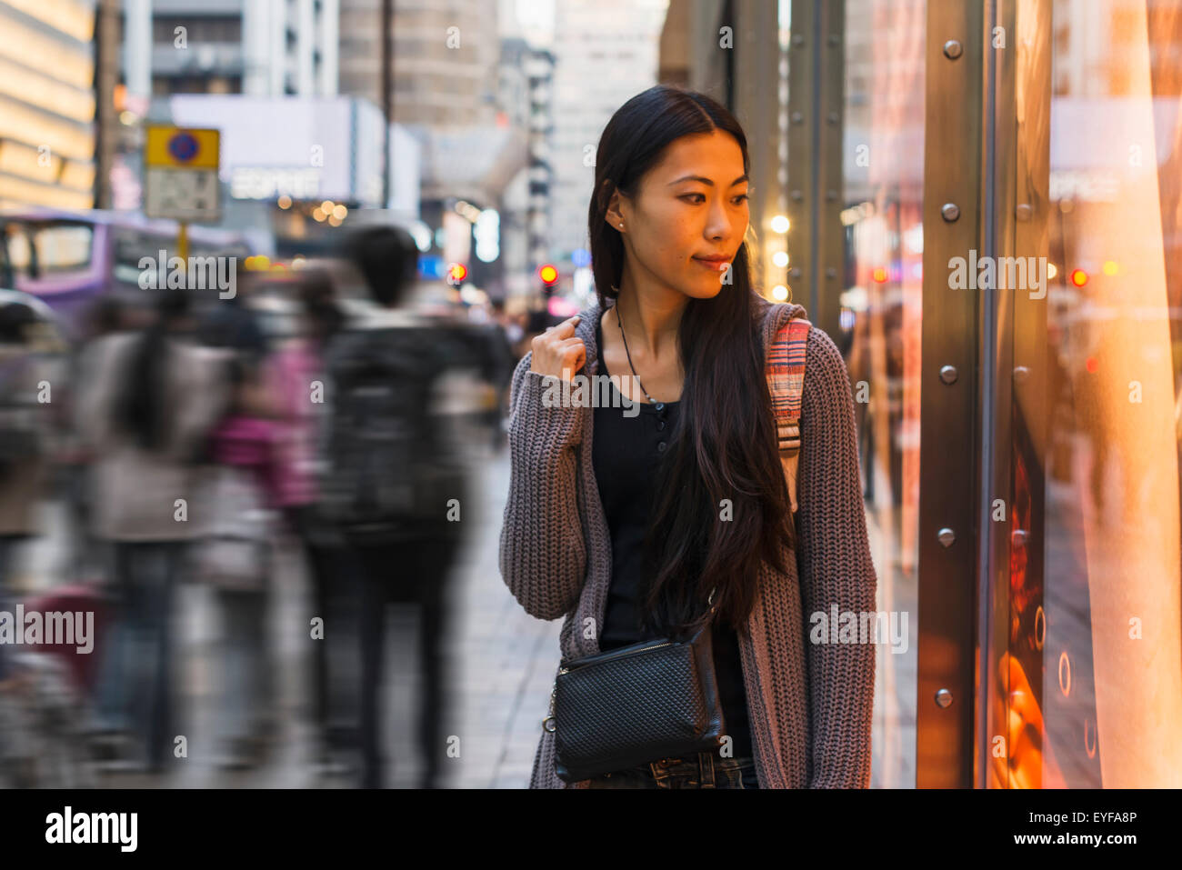 A young woman walking along the street and shops, Kowloon; Hong Kong, China Stock Photo