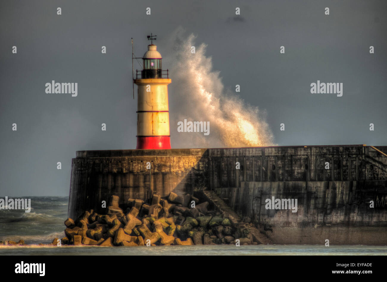 Newhaven, East Sussex, UK. 28th July, 2015. The Orange glow of Sunset light on the Lighthouse and waves driven by the strong wind..HDR Image Stock Photo