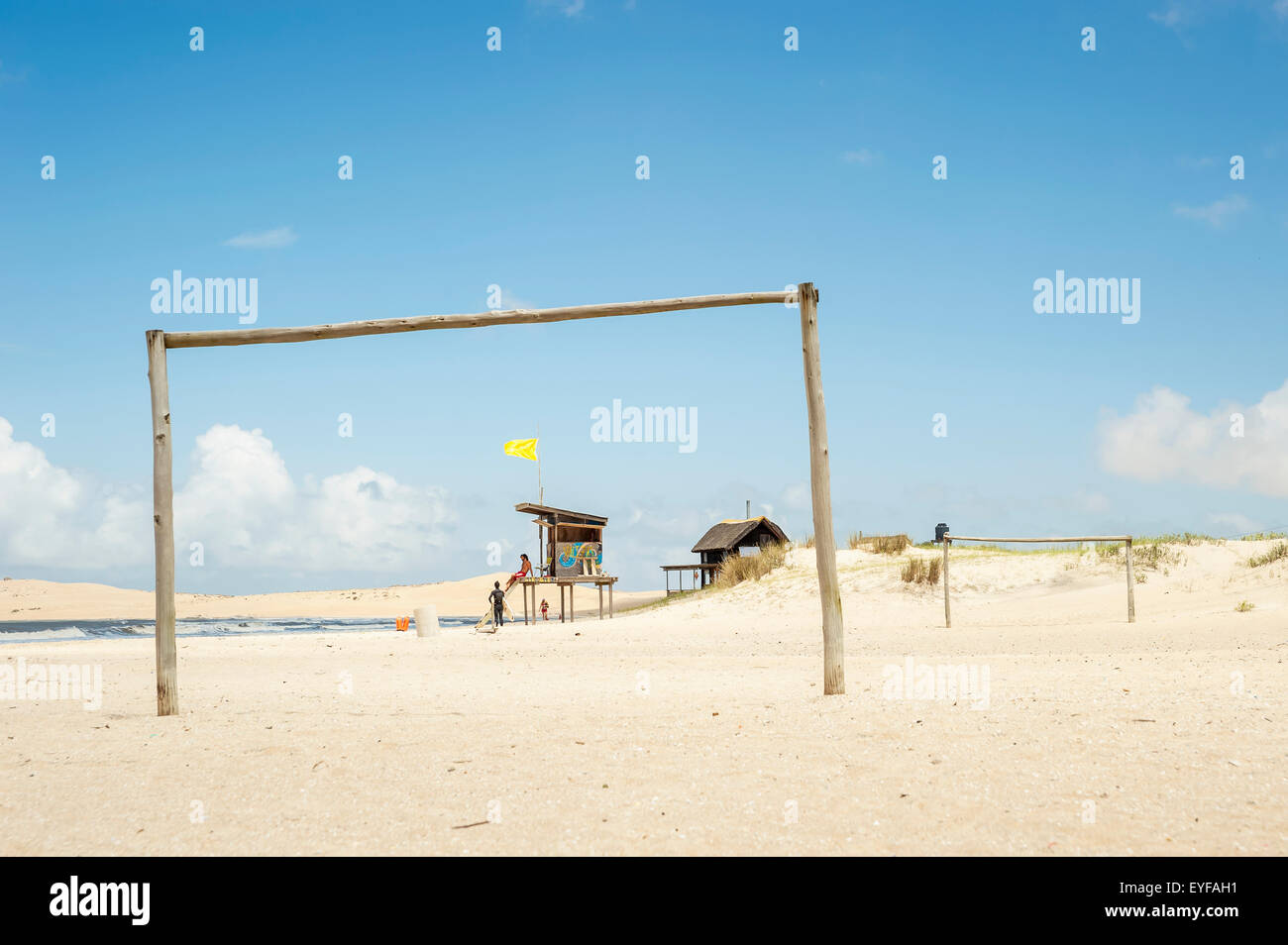 A wooden goal post on the beach with a lifeguard on duty in the background; Valizas, Uruguay Stock Photo