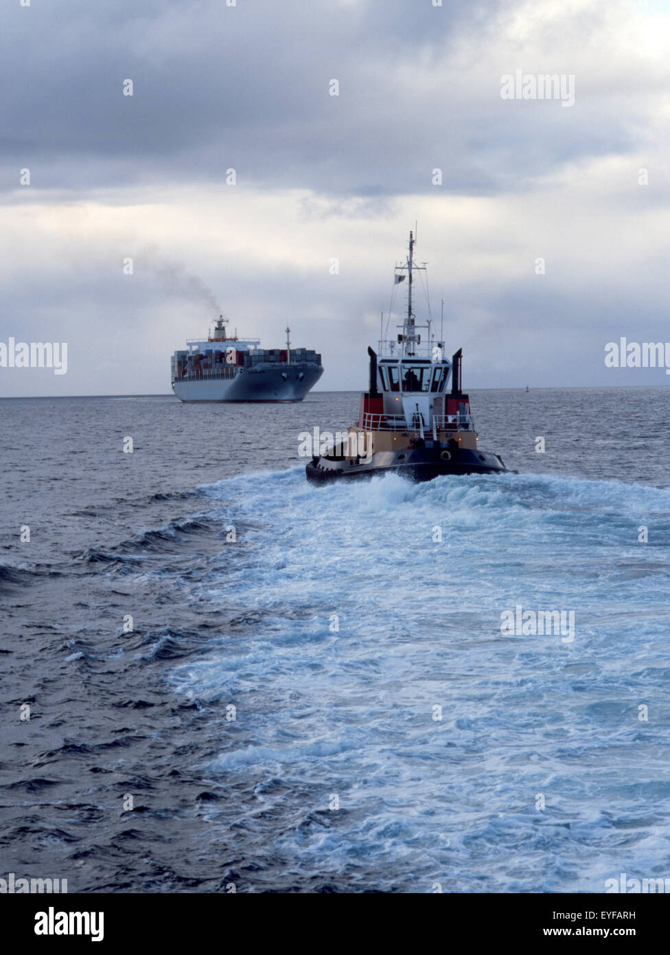 containership with tug assist Stock Photo