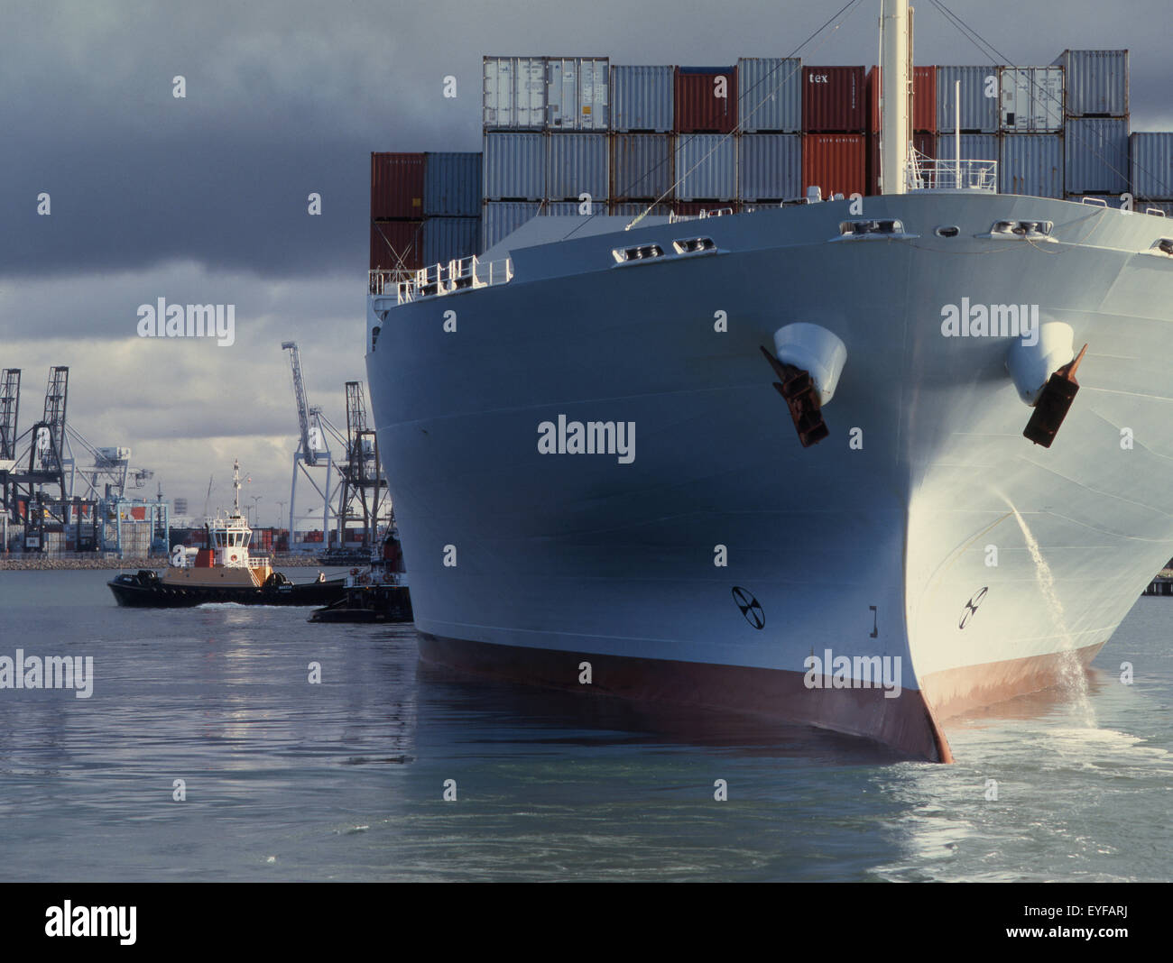 containership with tug assist with dramatic sky Stock Photo