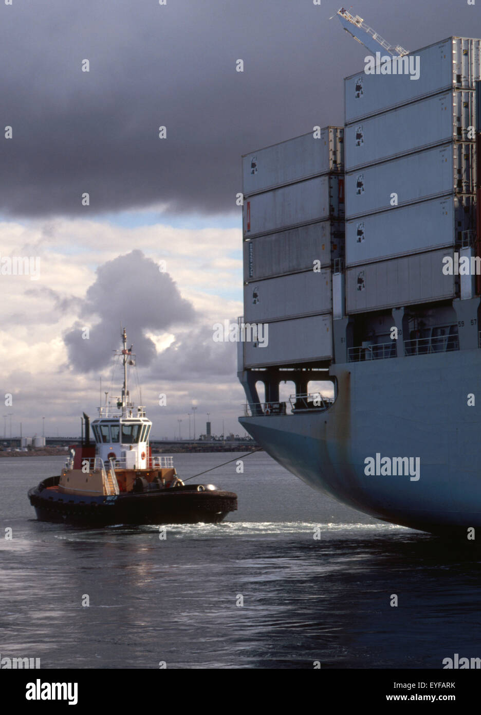 containership with tug assist with dramatic sky Stock Photo