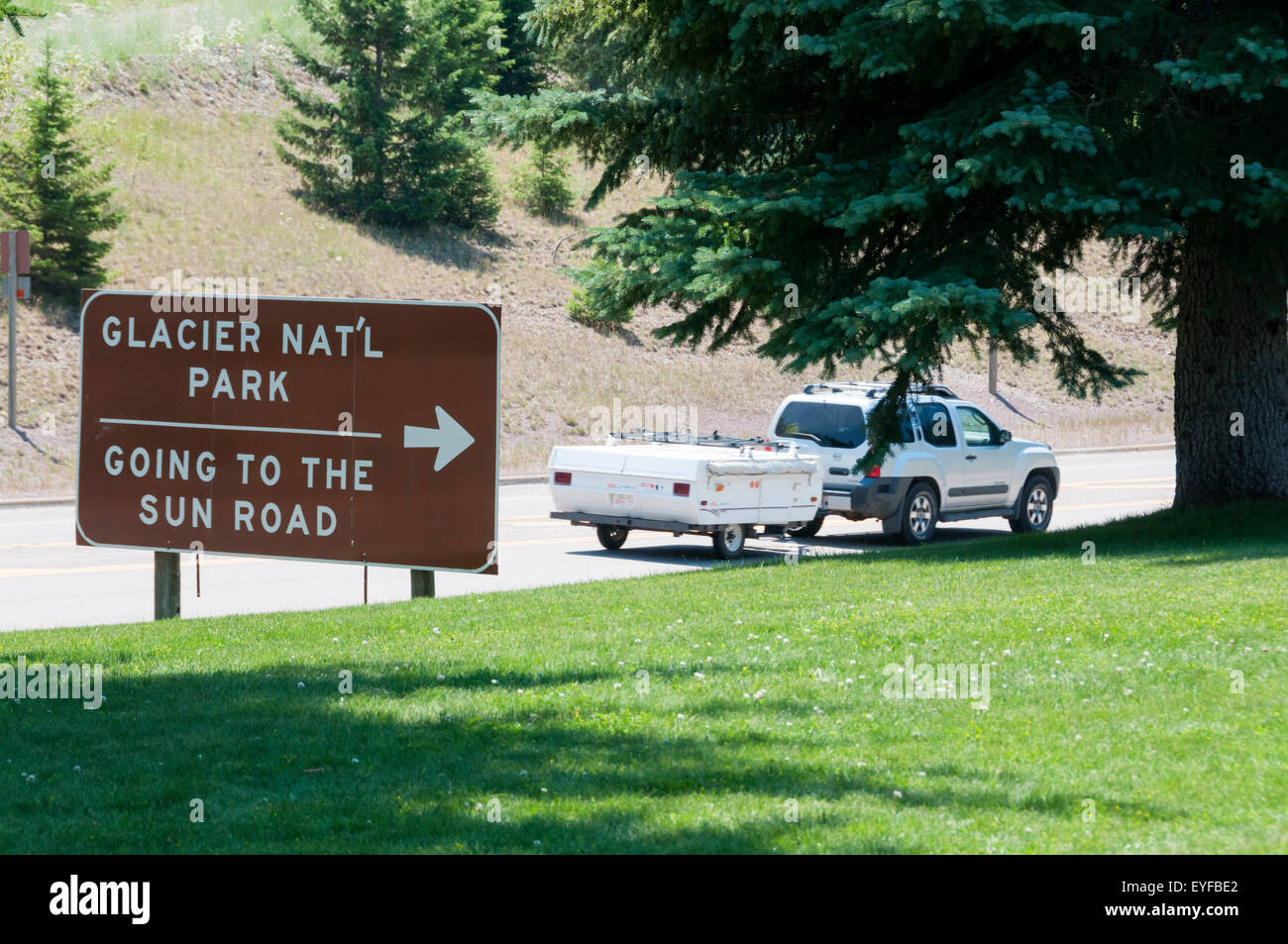 A sign for Going to the Sun Road in Glacier National Park, Montana, USA with a car towing a camping trailer (motion blurred). Stock Photo