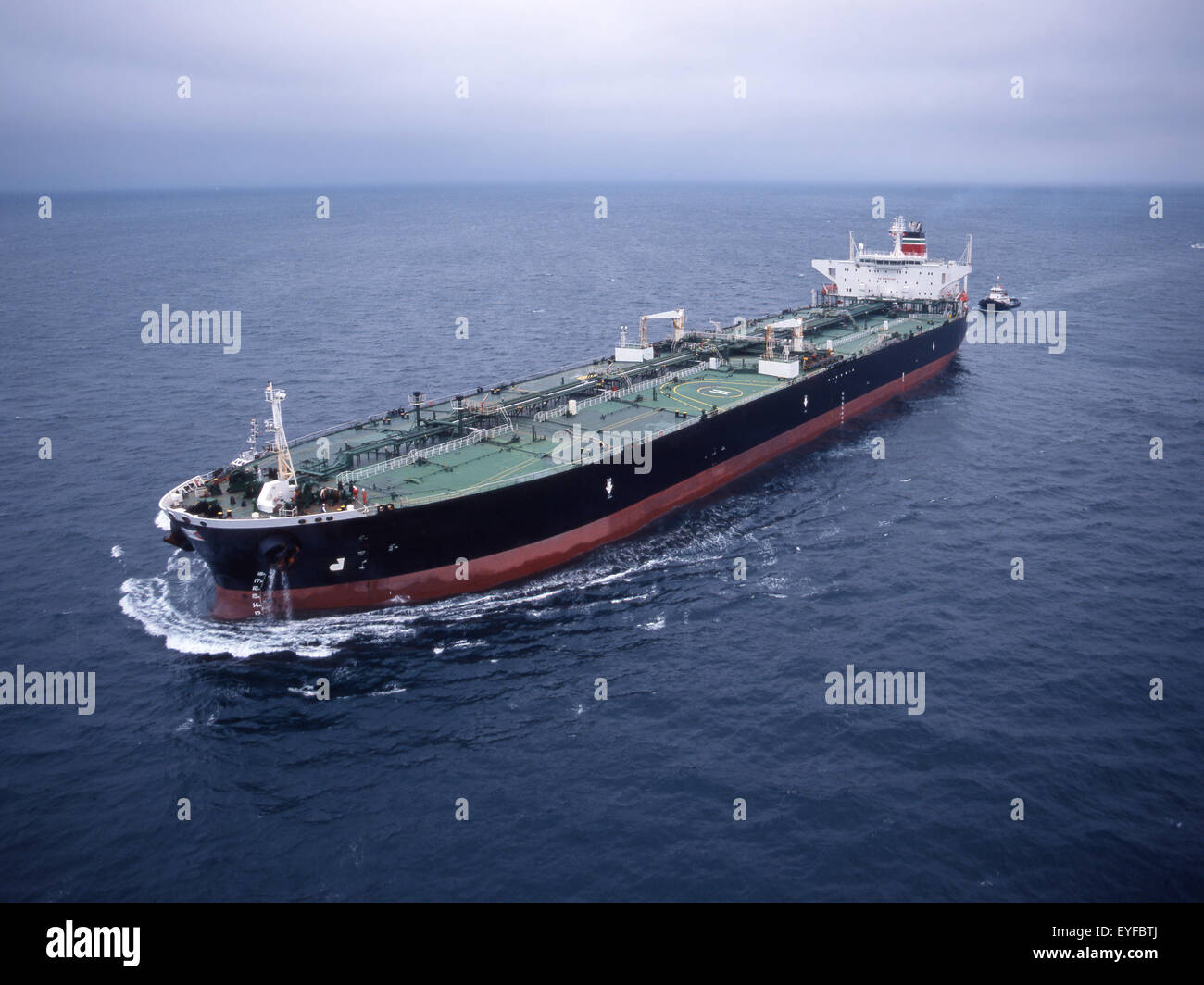 oil tanker steaming at sea with tug Stock Photo