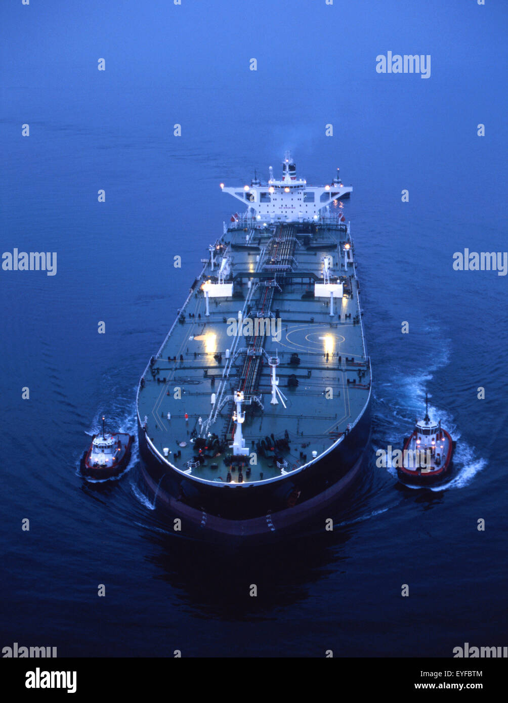 oil tanker with two tug boat assists pre-dawn aerial Stock Photo