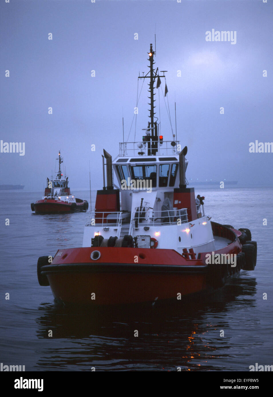 tugboats waiting for ship in pre-dawn light Stock Photo