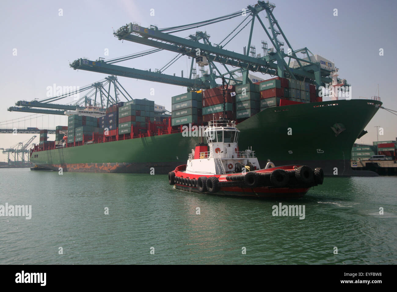 tugboat assisting containership to dock Stock Photo