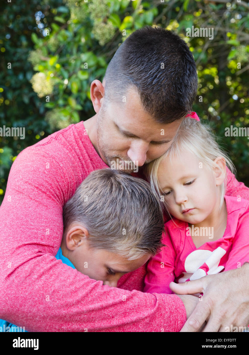 Father embracing son (10-11) and daughter (2-3) Stock Photo