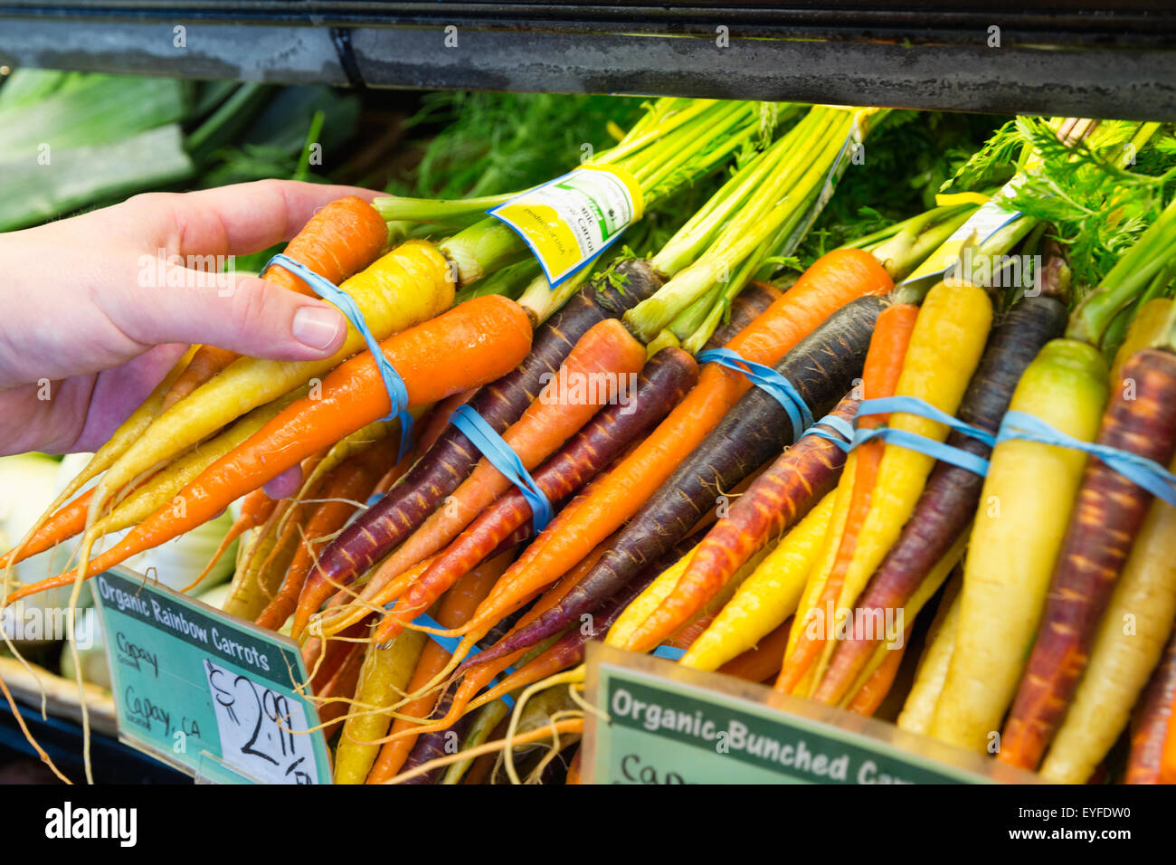 Man holding carrot in supermarket Stock Photo