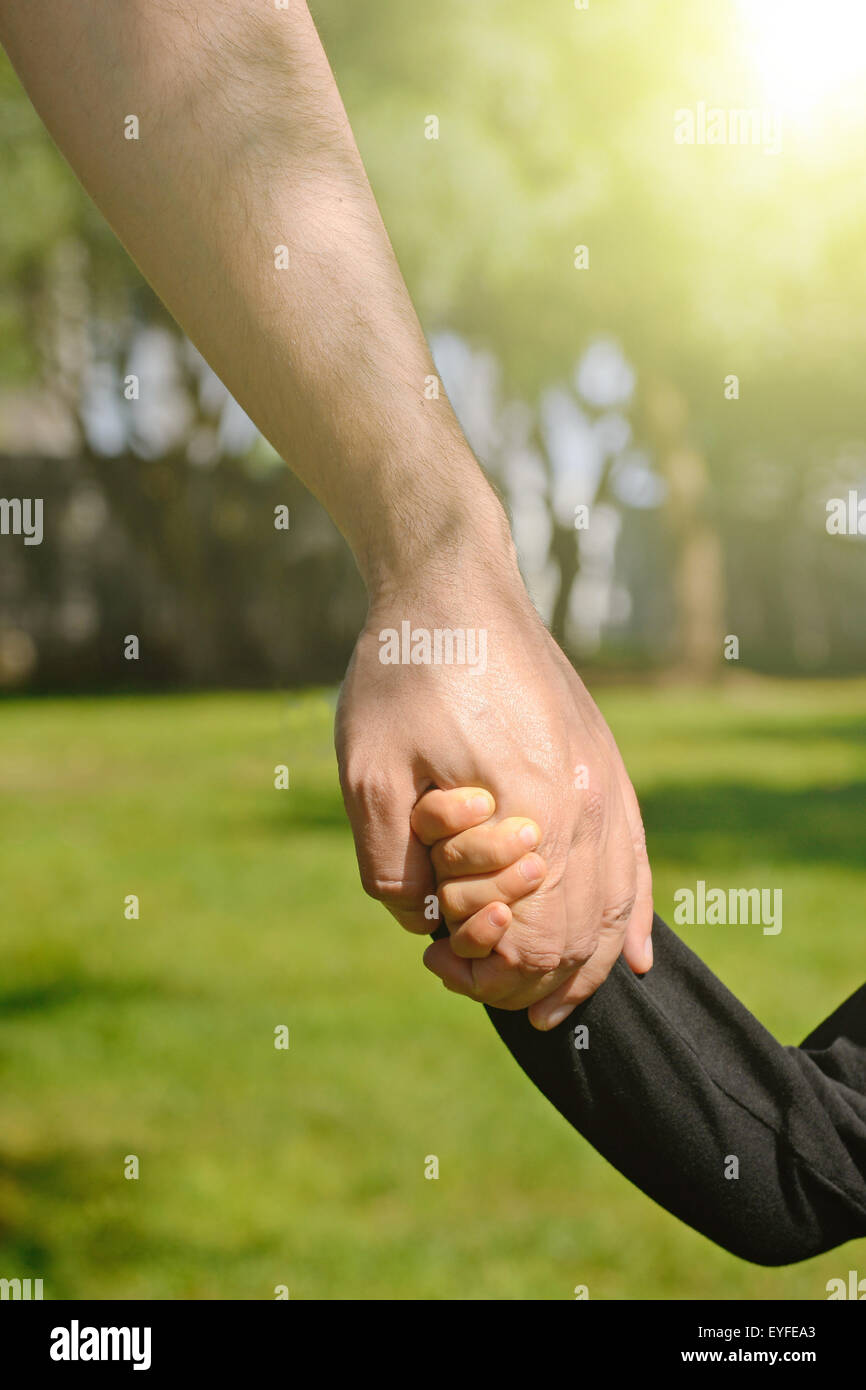 Closeup of a father and son holding hands in a park Stock Photo