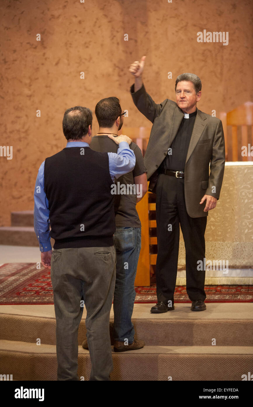 A teenage boy and his adult sponsor listen as their monsignor demonstrates procedure at a confirmation rehearsal at a Laguna Niguel, CA, Catholic church. Confirmation is one of the seven sacraments through which Catholics pass in the process of their religious upbringing. Stock Photo