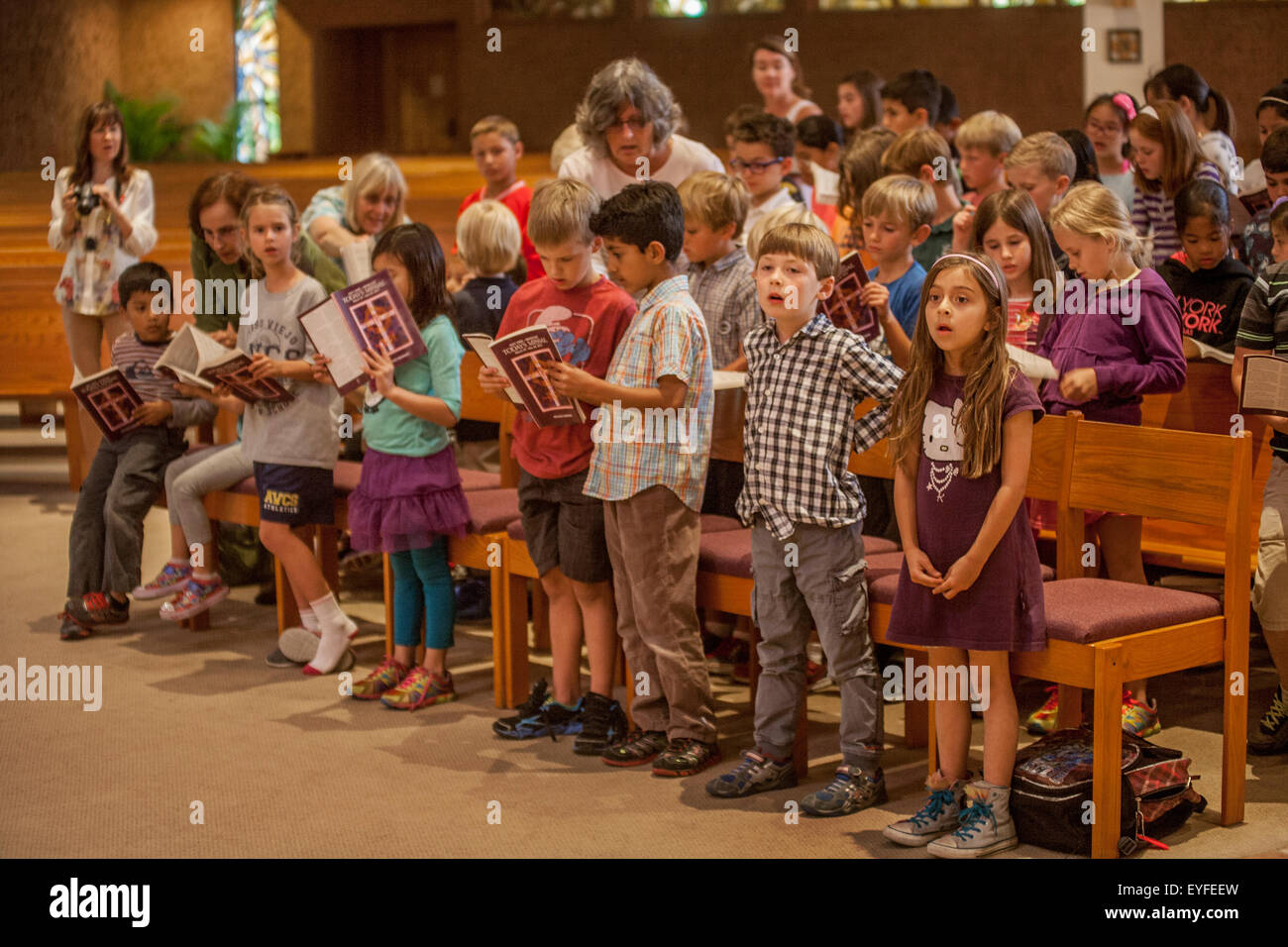 Multiracial children at a Laguna Niguel, CA, Catholic church consult their missals. A missal is a liturgical book containing all instructions and texts necessary for the celebration of Mass throughout the year. Stock Photo