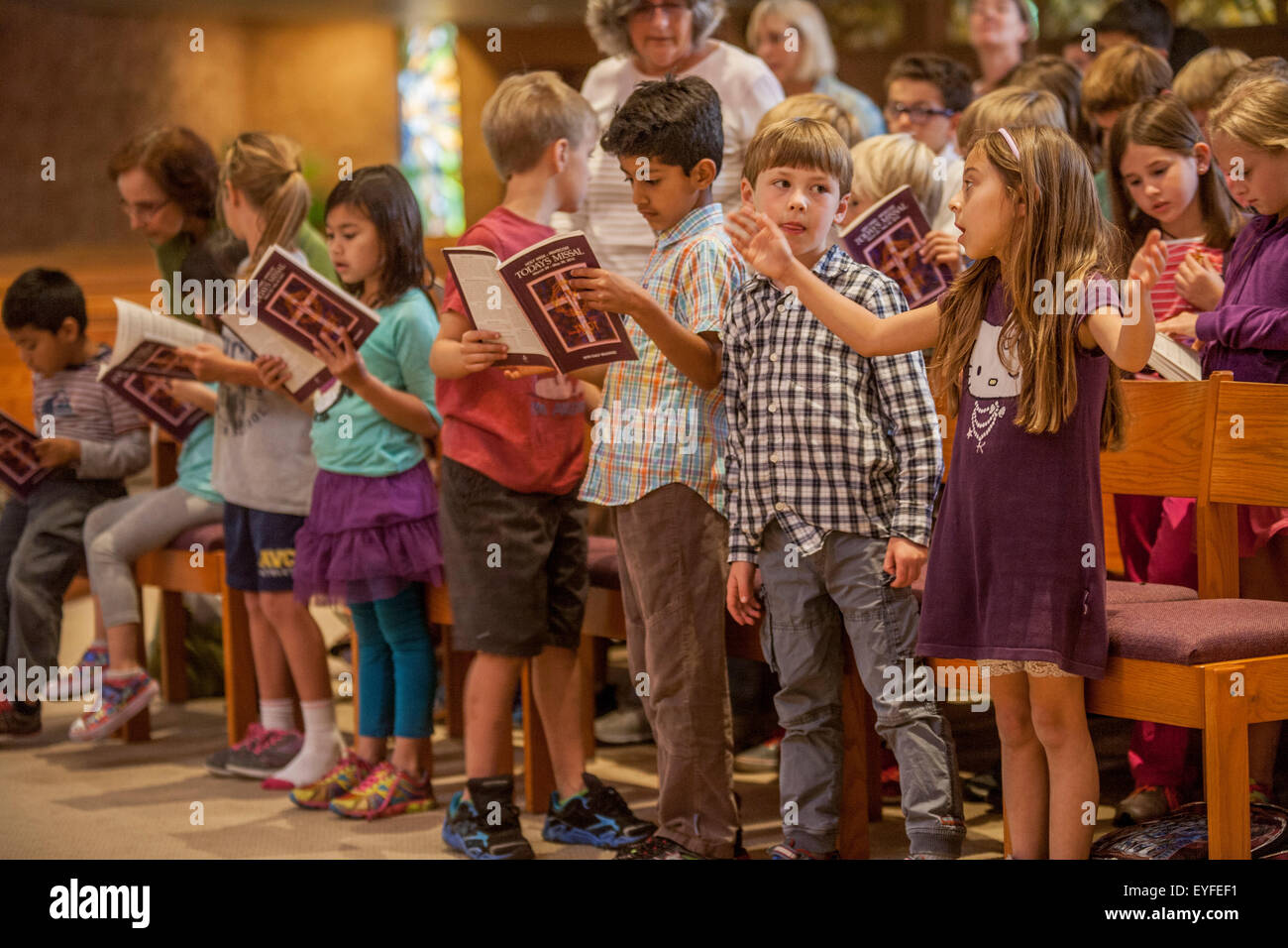 Multiracial children at a Laguna Niguel, CA, Catholic church consult their missals. A missal is a liturgical book containing all instructions and texts necessary for the celebration of Mass throughout the year. Stock Photo