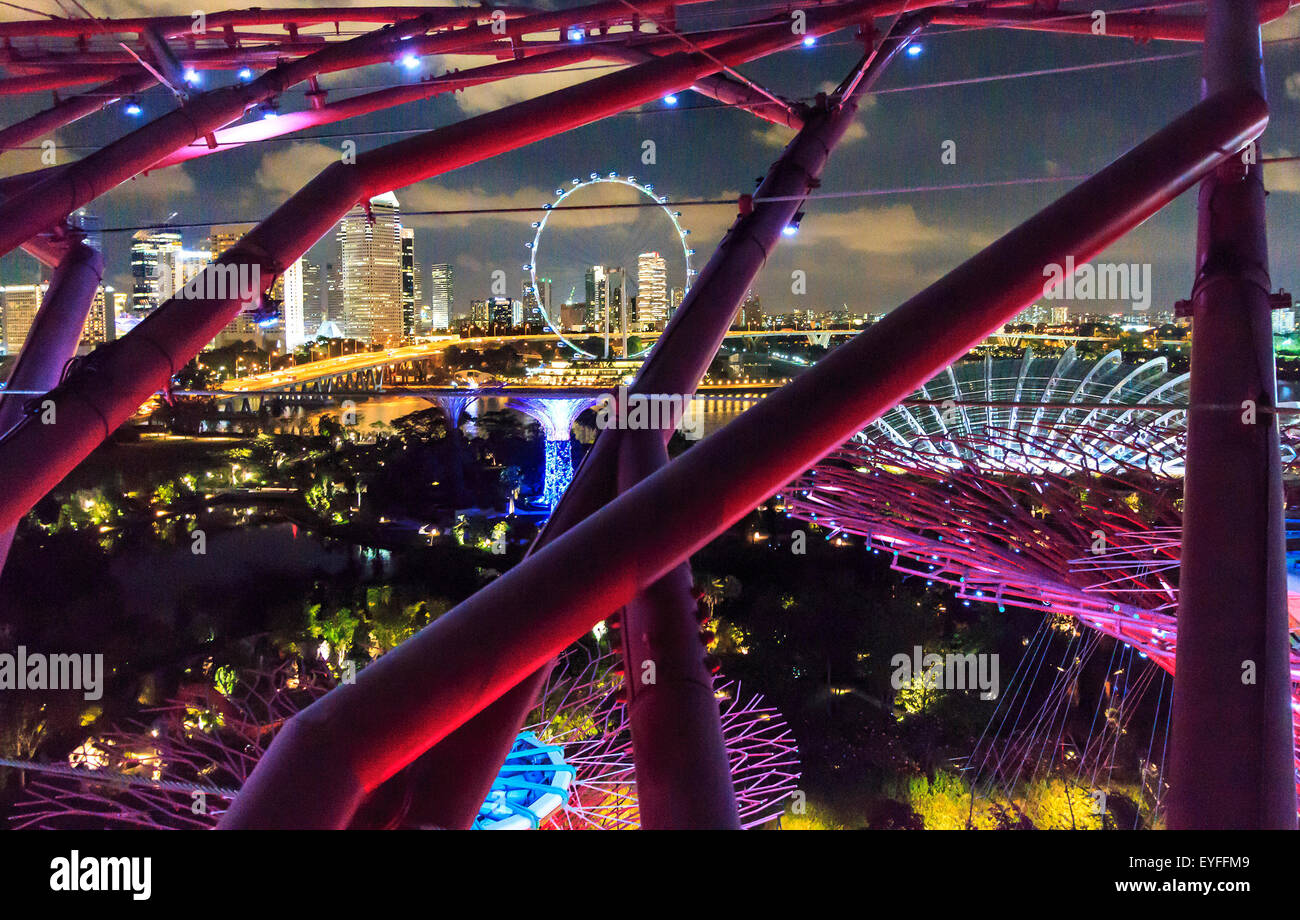 Singapore skyline including Singapore Flyer Ferris wheel, seen through support beams from observation deck on SuperTree Stock Photo