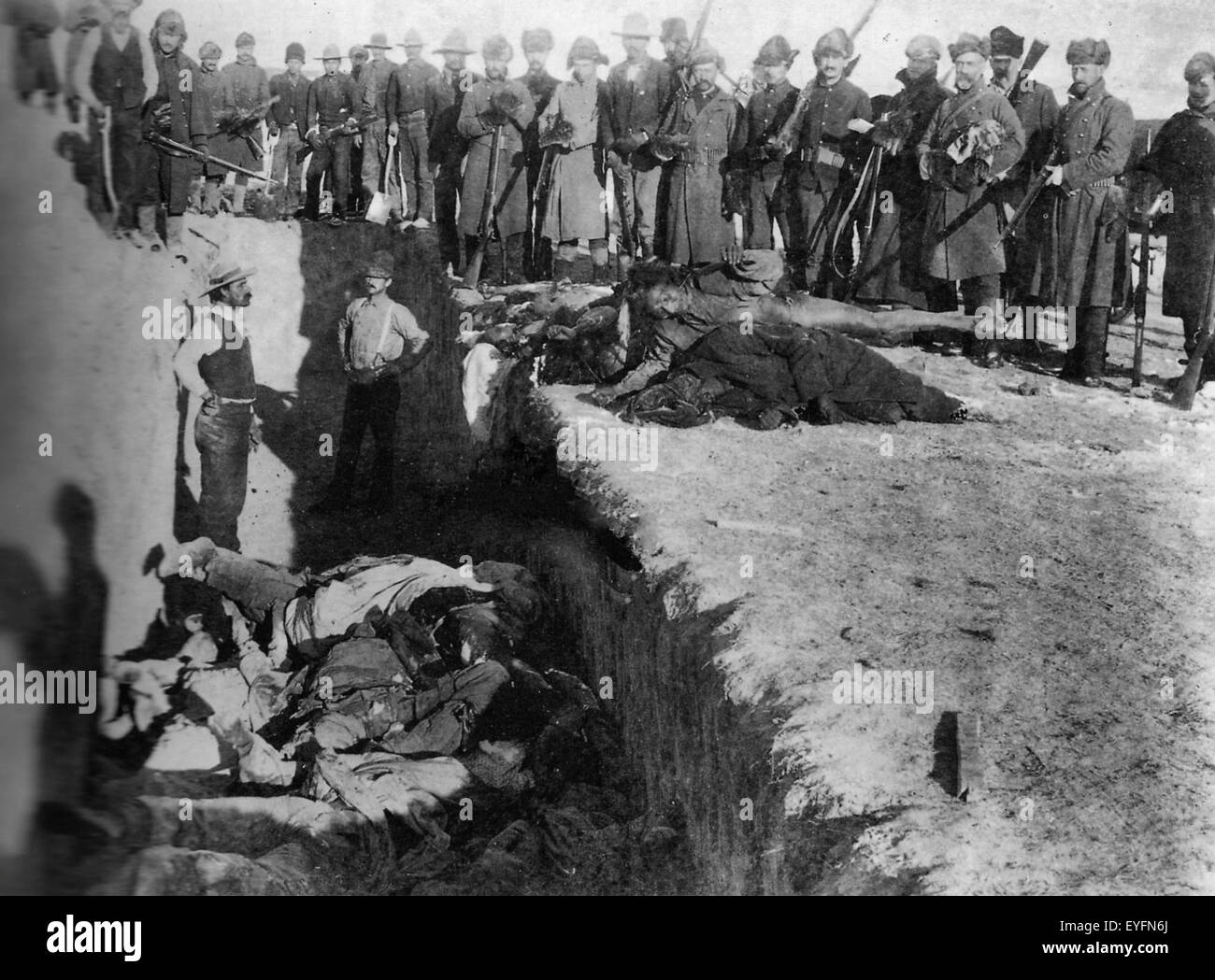 Burial of the dead after the massacre of Wounded Knee. U.S. Soldiers putting Indians in common grave; some corpses are frozen in different positions. South Dakota   1891 Stock Photo