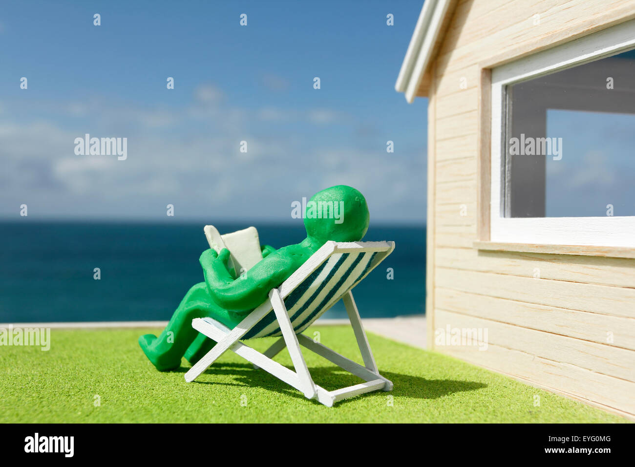 Model House and Plasticine Person in Deck Chair Stock Photo