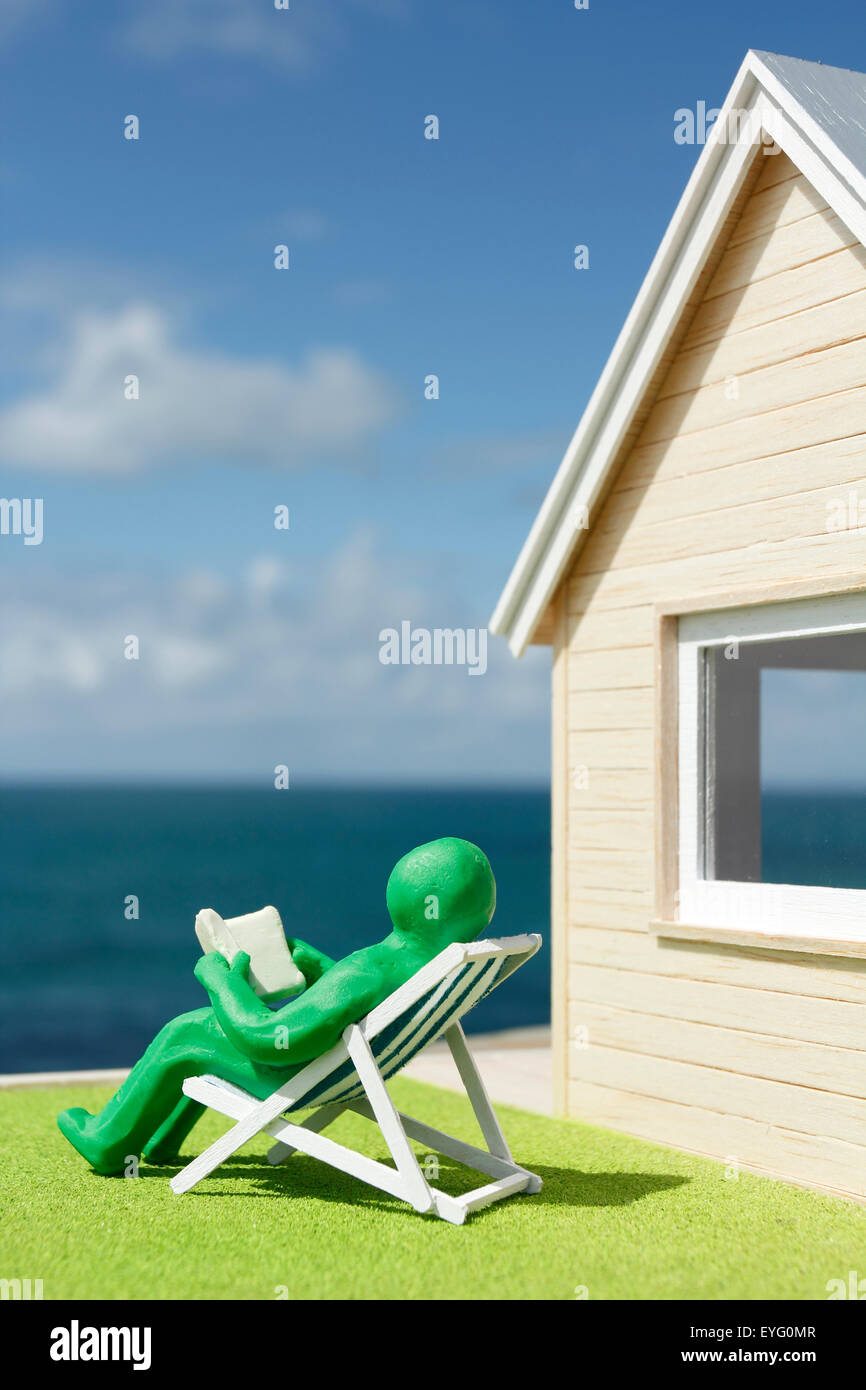 Model House and Plasticine Person in Deck Chair Stock Photo