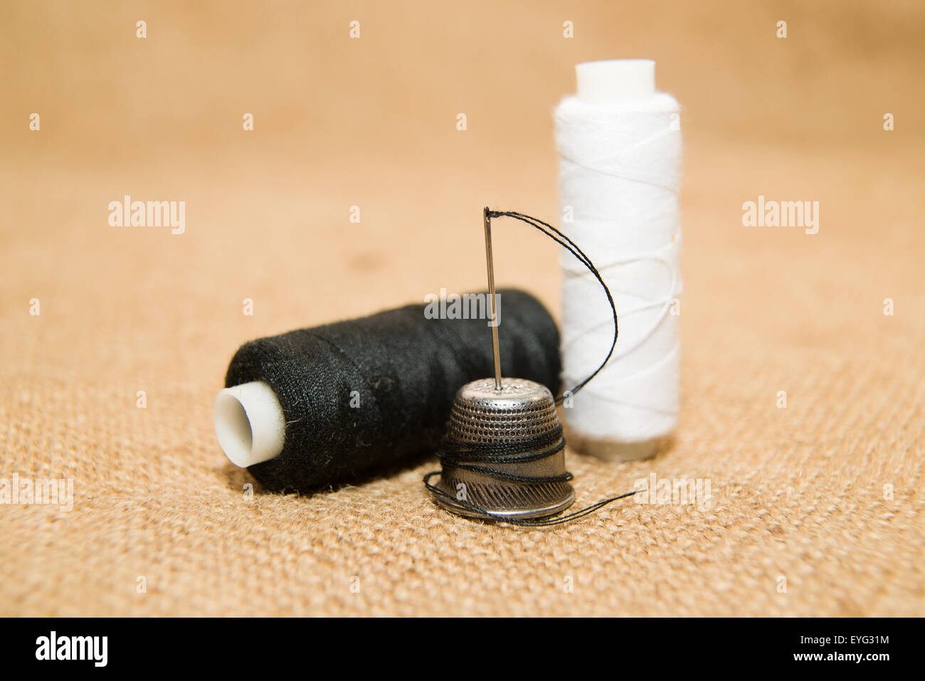 Sewing Needle, thimble and thread spool on the old cloth Stock Photo Alamy