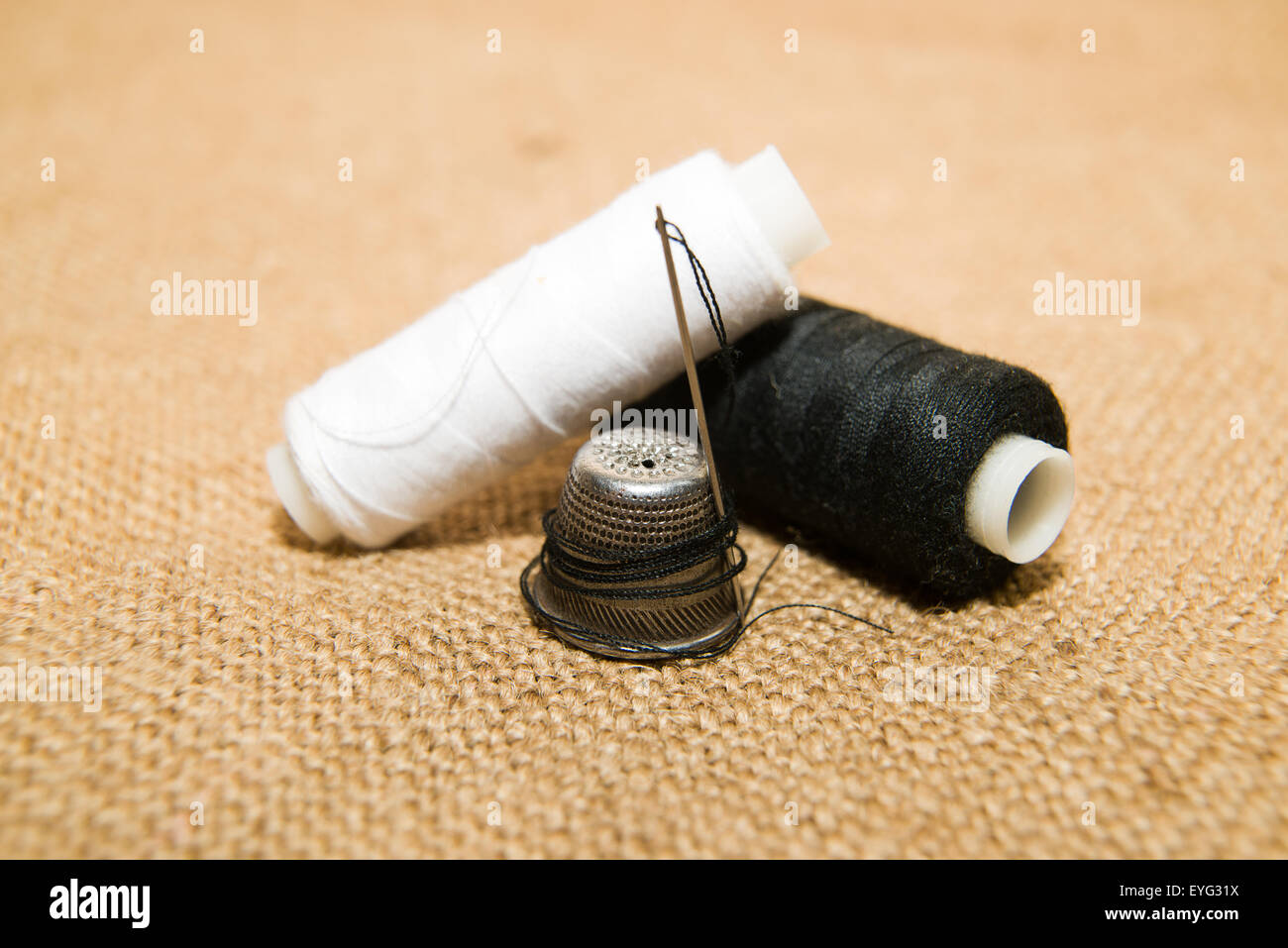 Sewing Needle, thimble and thread spool on the old cloth Stock Photo Alamy